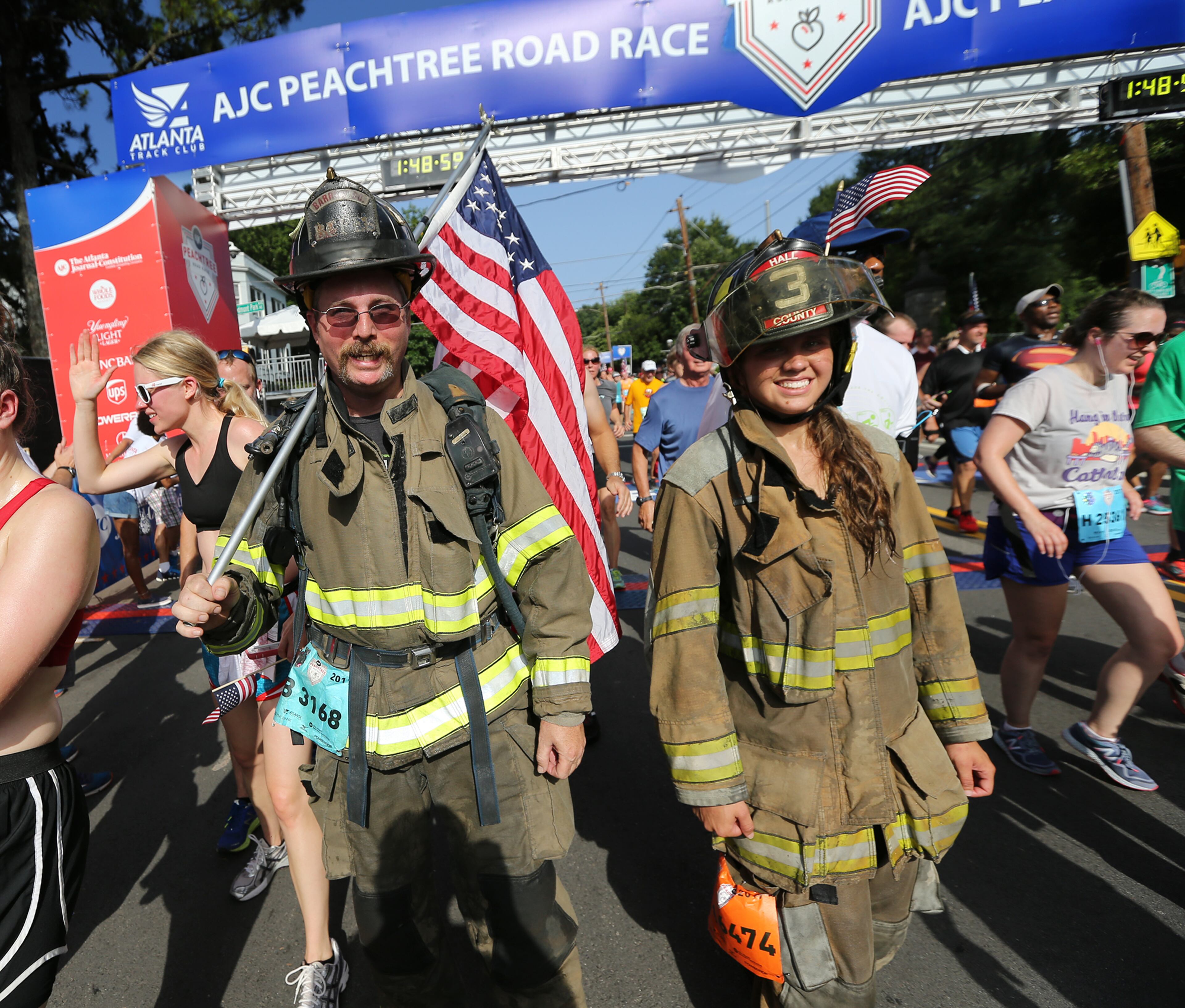 July 04, 2017 Atlanta: Barrow County Firefighter Sean Gluth and Hall County firefighter Ashley Wilkens finish the 6.2 mile course wearing full gear during the 48th running of the AJC Peachtree Road Race on Tuesday, July 4, 2017, in Atlanta. Curtis Compton/ccompton@ajc.com