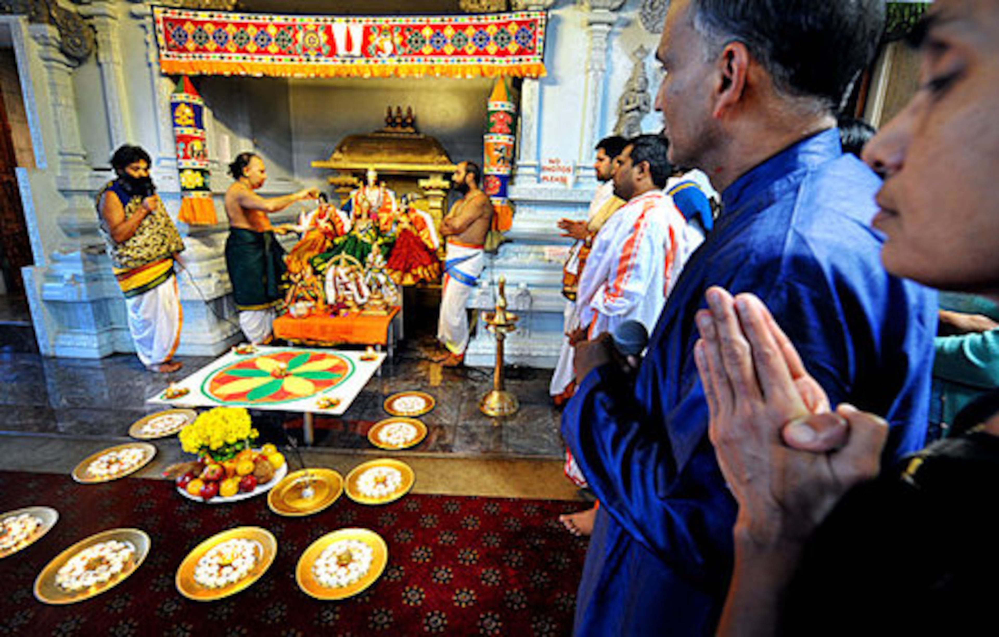 P. Ravi Sarma (second from right), president of the Hundu Temple of Atlanta, and his wife, Seshu Sarma (far right), pray, while temple priests chant.