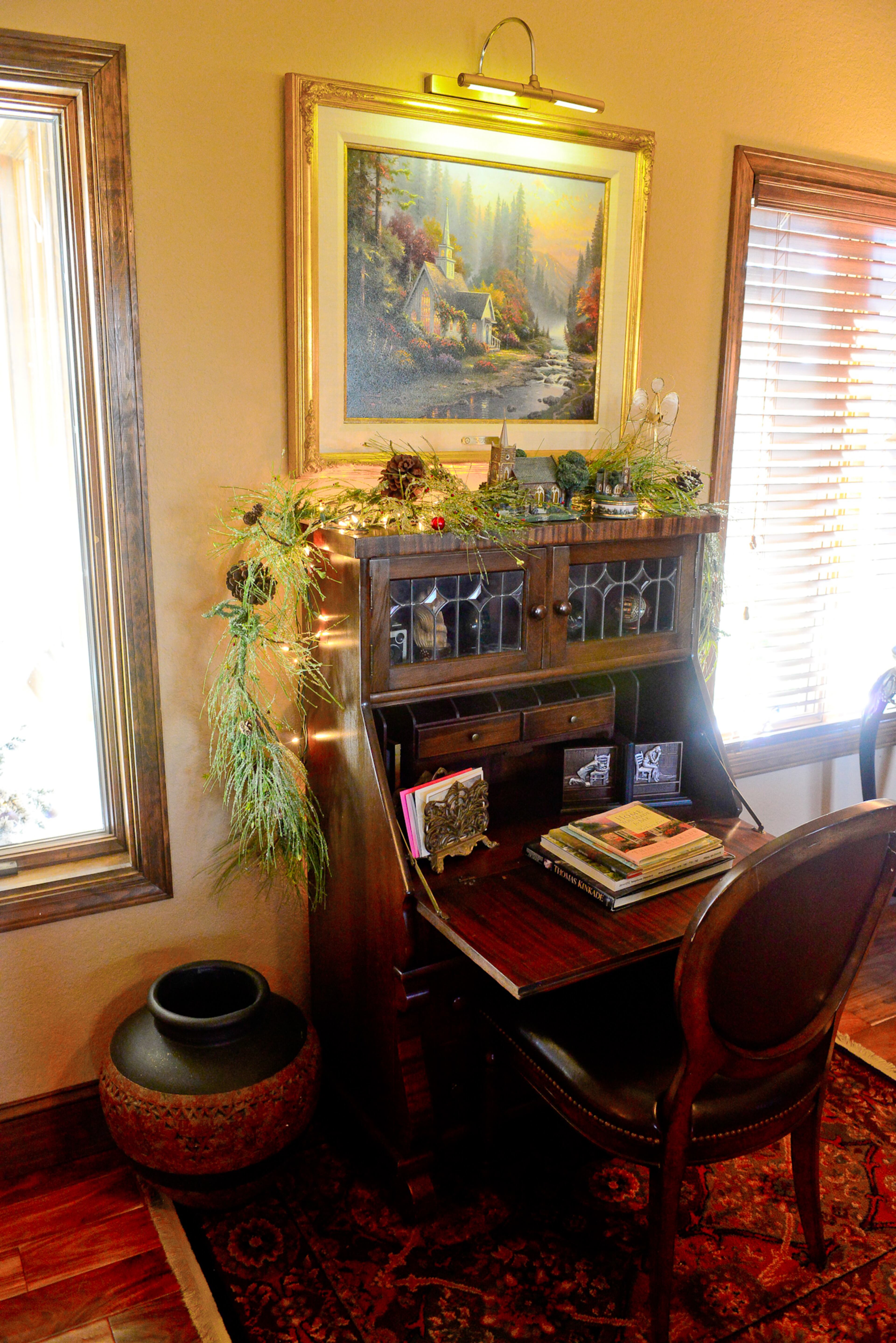 Thomas Kinkade paintings, accented by picture lighting, fit with the home's bucolic setting on 10 acres on top of a ridge in north Georgia. The homeowners have an array of antique furniture.