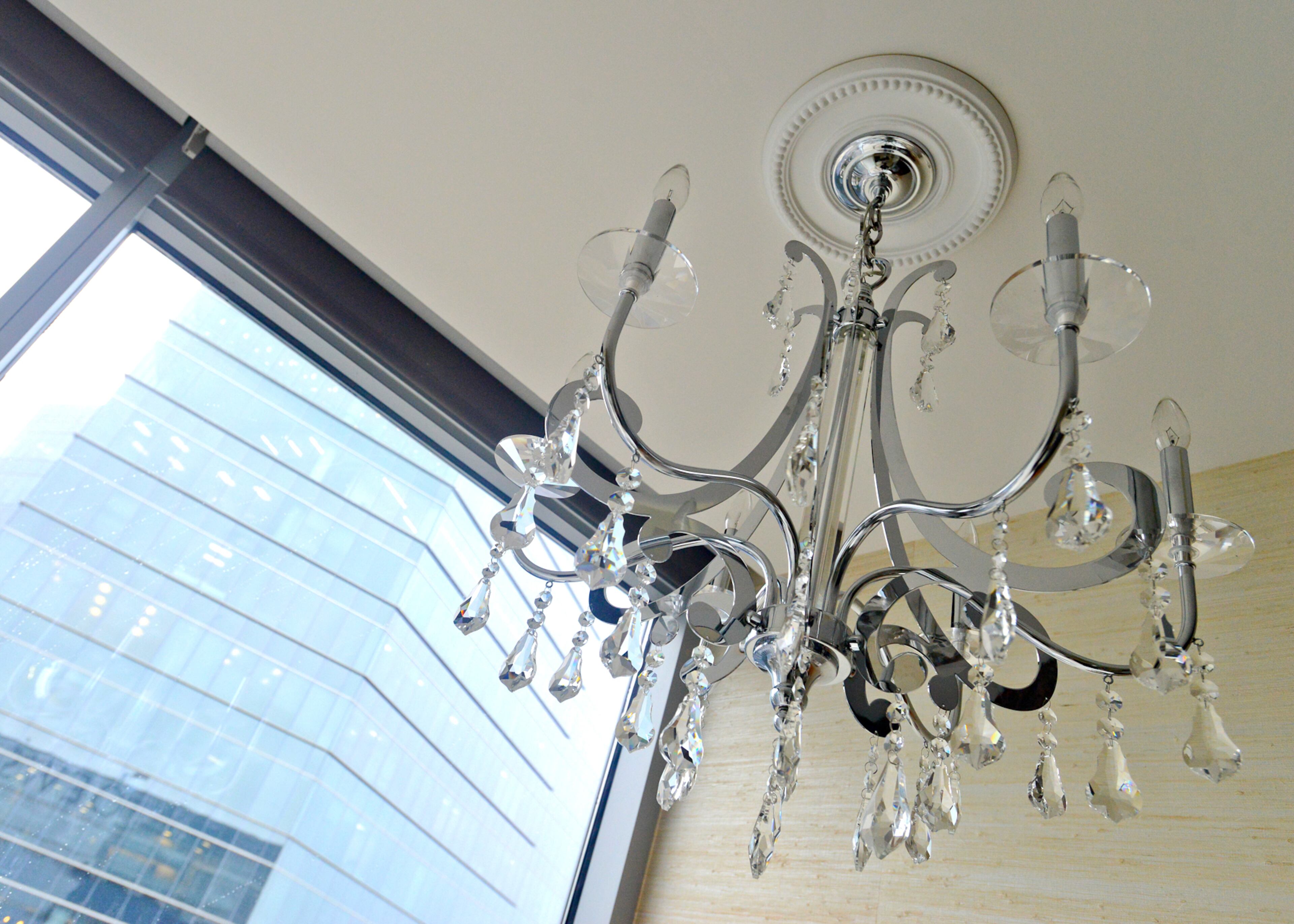 A chandelier from Masterpiece Lighting brightens the white metallic sisal wallpaper in Jim Wilson's Midtown master bathroom, which overlooks the city below.