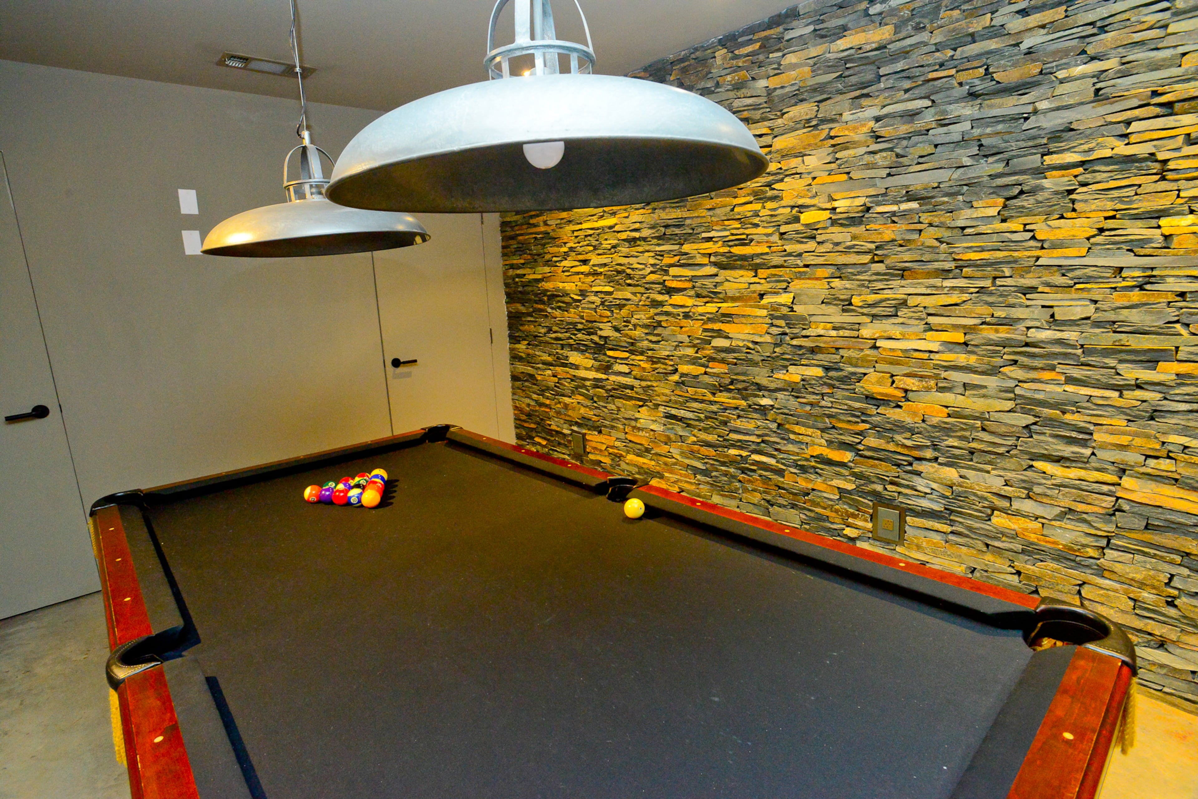 The Virginia-Highland home, built in 2014, has entertaining spaces such as a pool room in the basement, which also features the stunning stone walls found throughout the house. Light fixtures are from Lighting Loft.