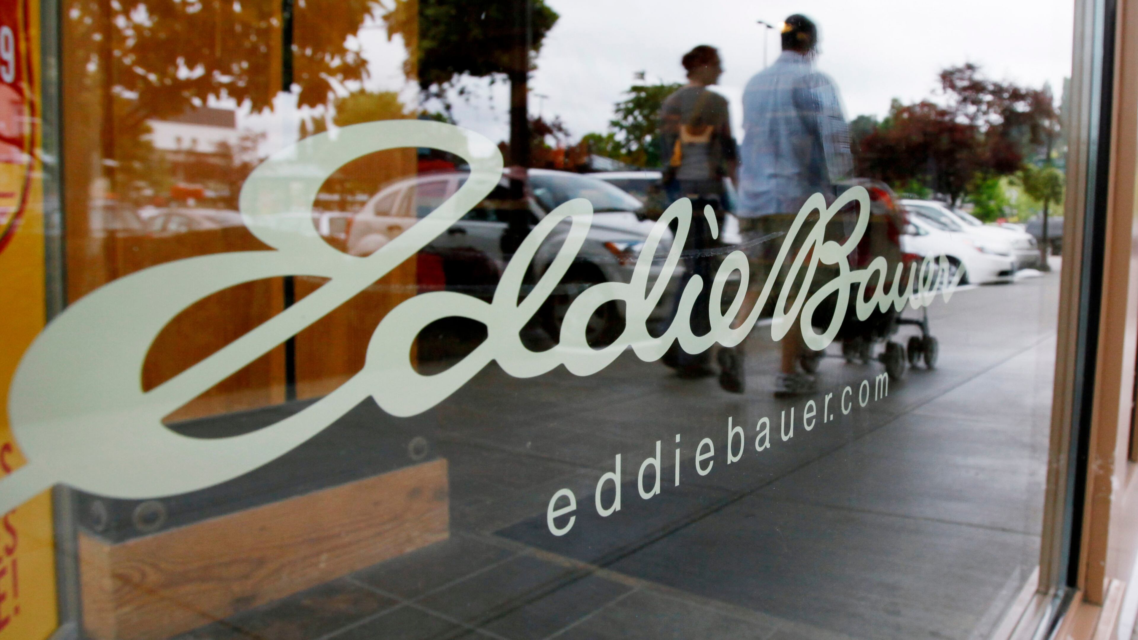 FILE - In this June 17, 2009, file photo, shoppers are reflected in the window as they walk past an Eddie Bauer store, in Seattle. (AP Photo/Elaine Thompson, File)