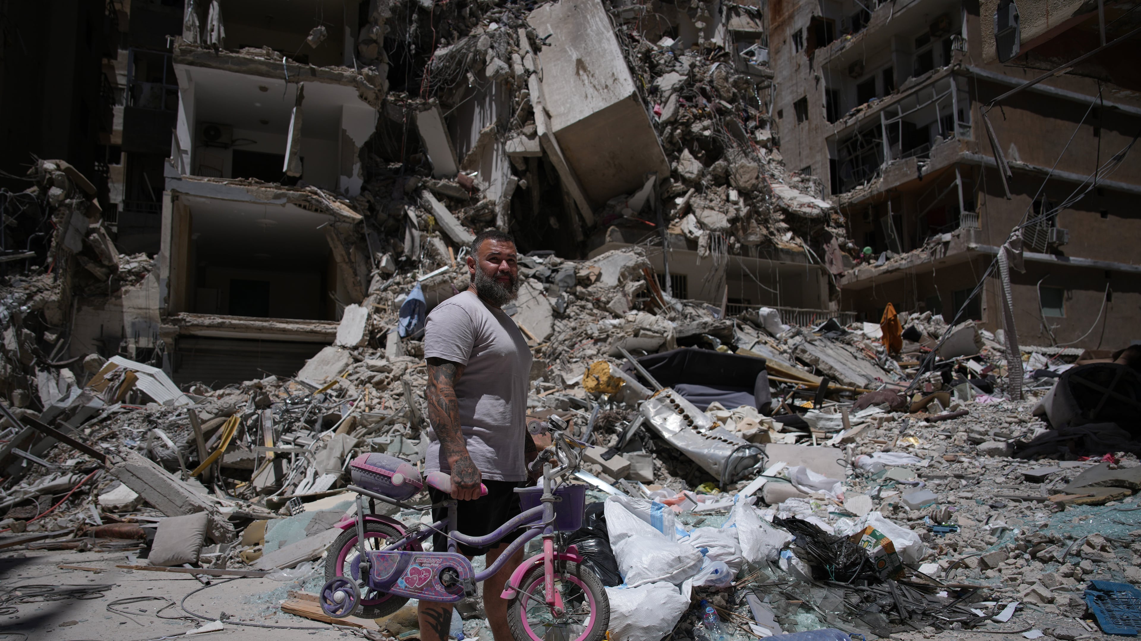 Barber Wissam Srour, 41, holds his daughter's bicycle recovered from his barbershop as he searches for belongings in the rubble of the shop, damaged in an Israeli strike, in the southern port city of Tyre, Lebanon, Friday, June 19, 2026. (AP Photo/Hassan Ammar)