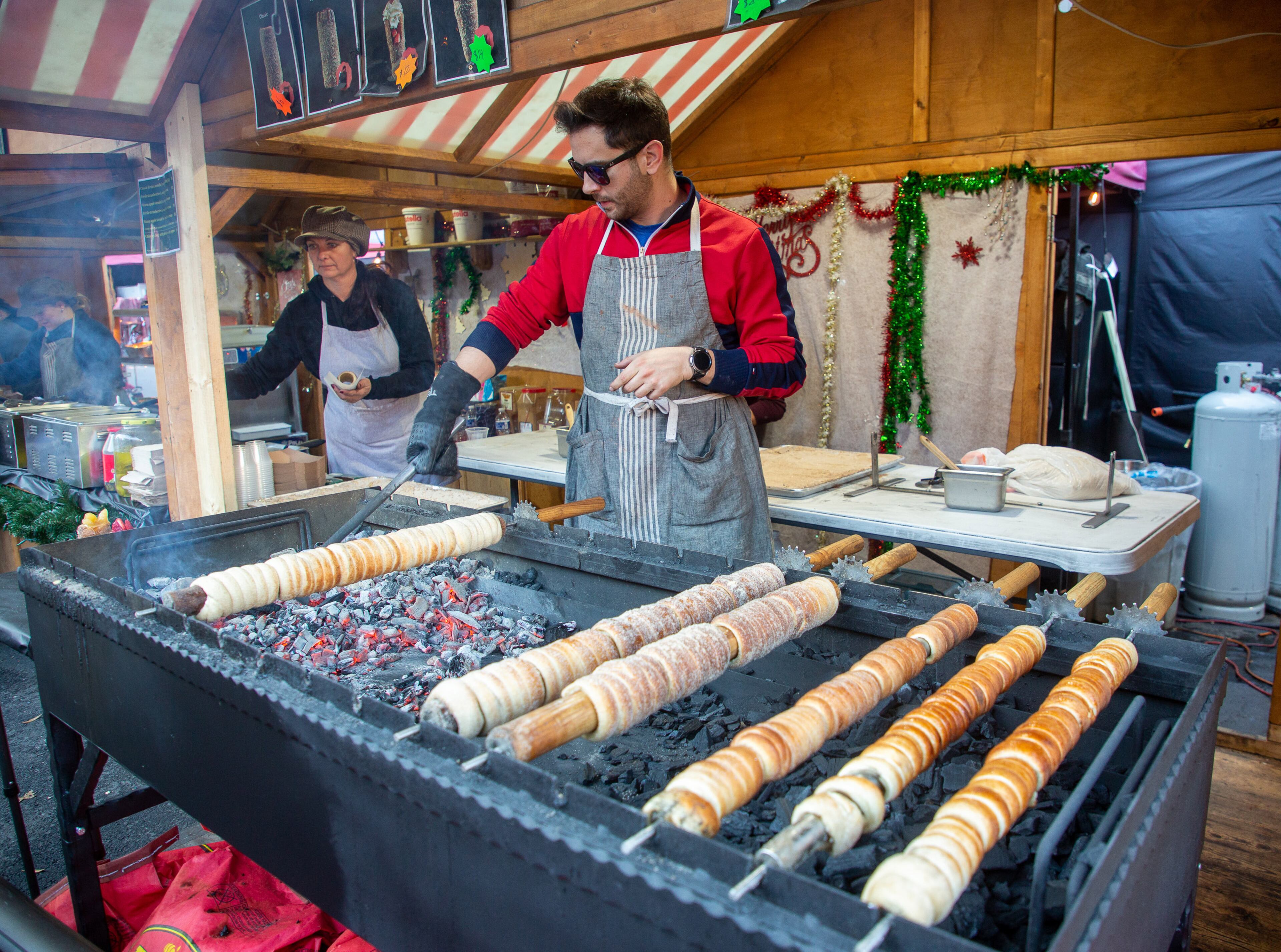 Fei Fkip makes chimney cakes at the Atlanta Christkindl Market on Sunday, December 12, 2021. STEVE SCHAEFER FOR THE ATLANTA JOURNAL-CONSTITUTION