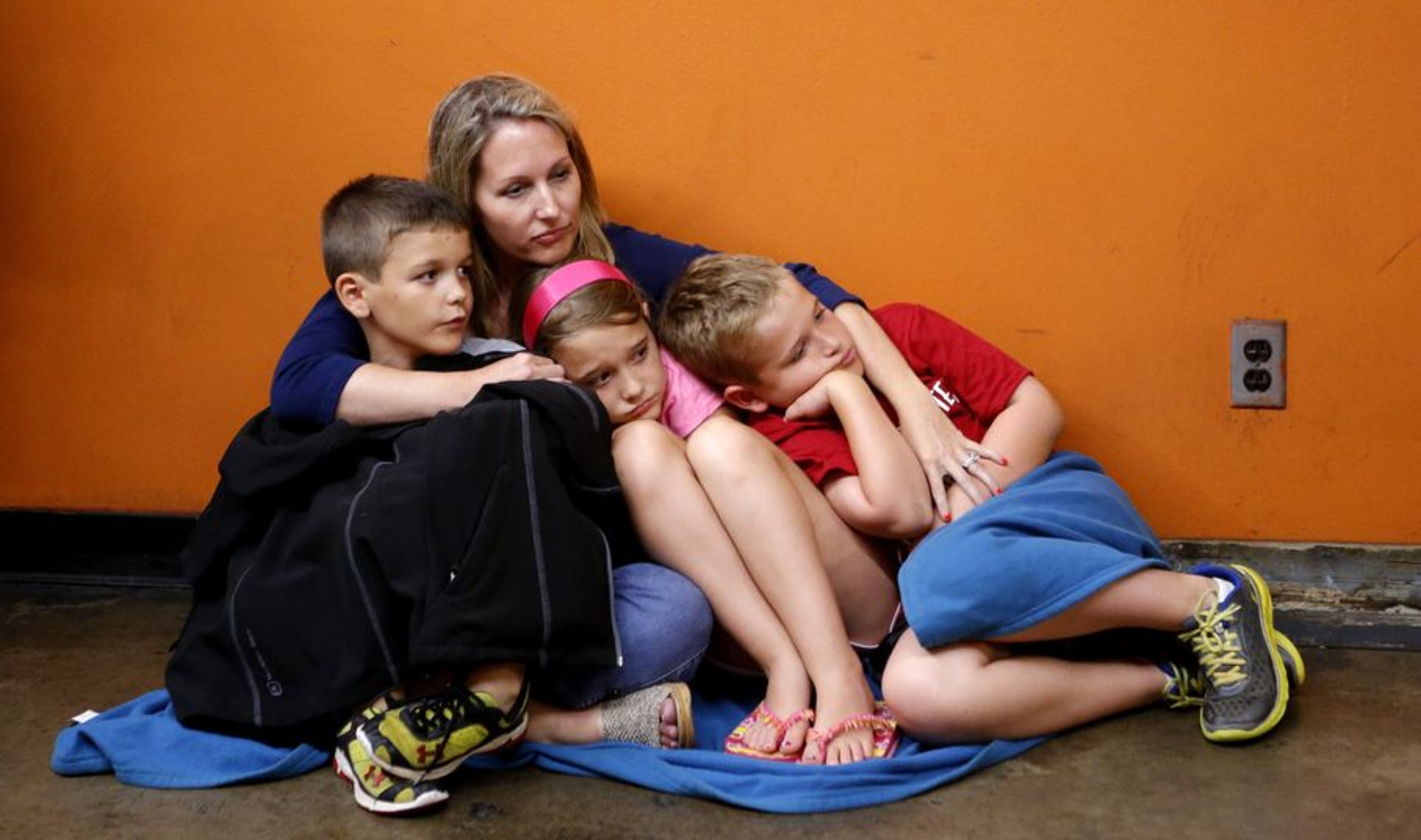 Lisa Ludlam holds her children, Jake, 6, Paige, 9, and Tony, 11, under the Cox Convention Center after fans at the Barons game were evacuated to the parking garage under the Cox Convention Center due to severe storms in Oklahoma City on Friday, May 31, 2013. Emergency officials set out Saturday morning to see how much damage a violent burst of thunderstorms and tornadoes caused as it swept across the Midwest overnight, killing at least five and injuring dozens. The storm toppled cars and left commuters trapped on an interstate highway as it bore down during Friday's evening rush hour near Oklahoma City. The National Weather Service reported "several" tornadoes rolled in from the prairie, terrifying towns along their paths. (AP Photo/The Oklahoman, Bryan Terry)