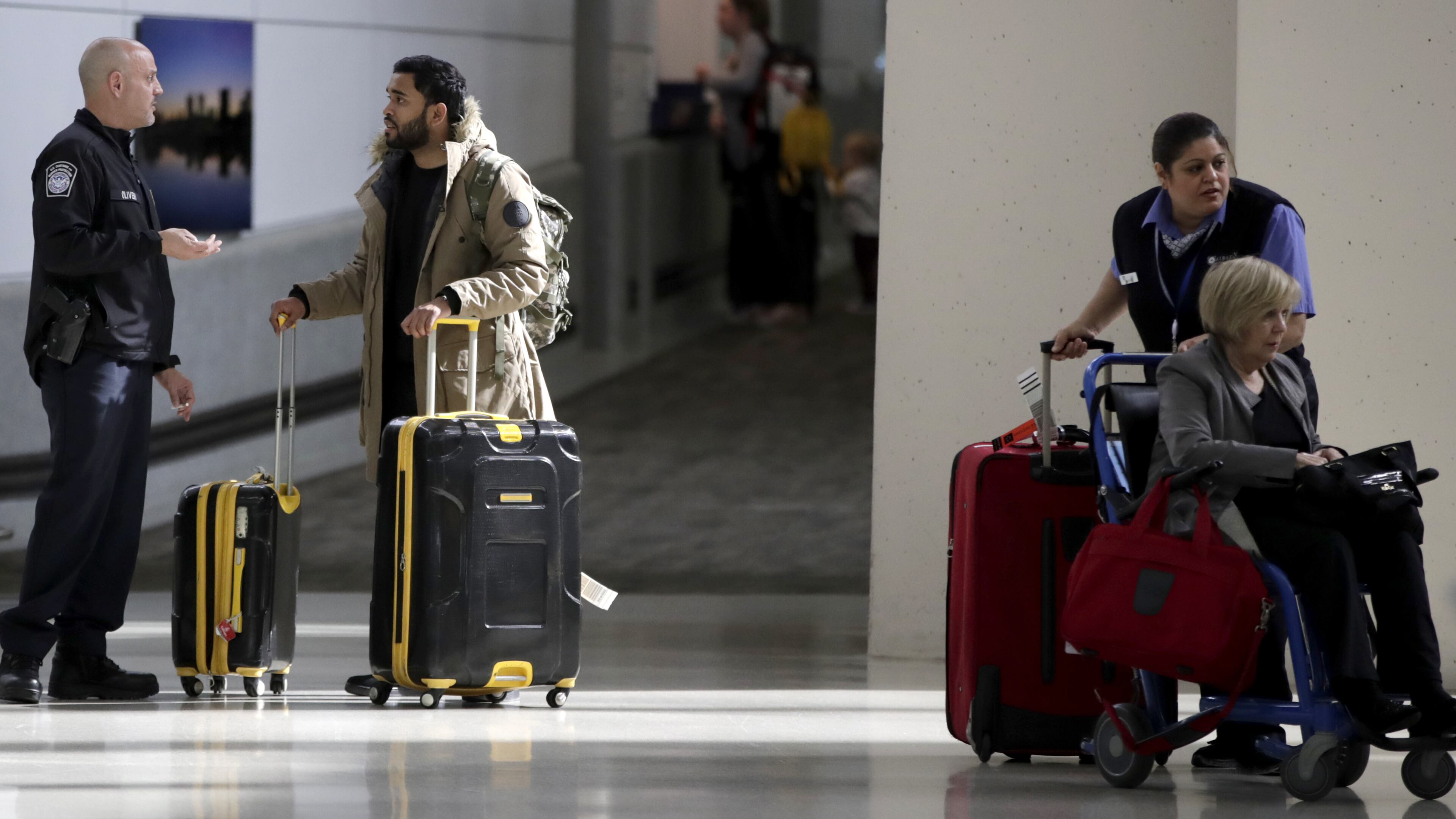 A traveler, second from left, talks to a U.S. Customs and Border Protection official near the exit of the international arrivals terminal at Newark Liberty International Airport, Thursday, Oct. 26, 2017, in Newark, N.J. . Long-haul carriers are starting new screening procedures for U.S.-bound passengers after receiving new security guidelines from American authorities. (AP Photo/Julio Cortez)