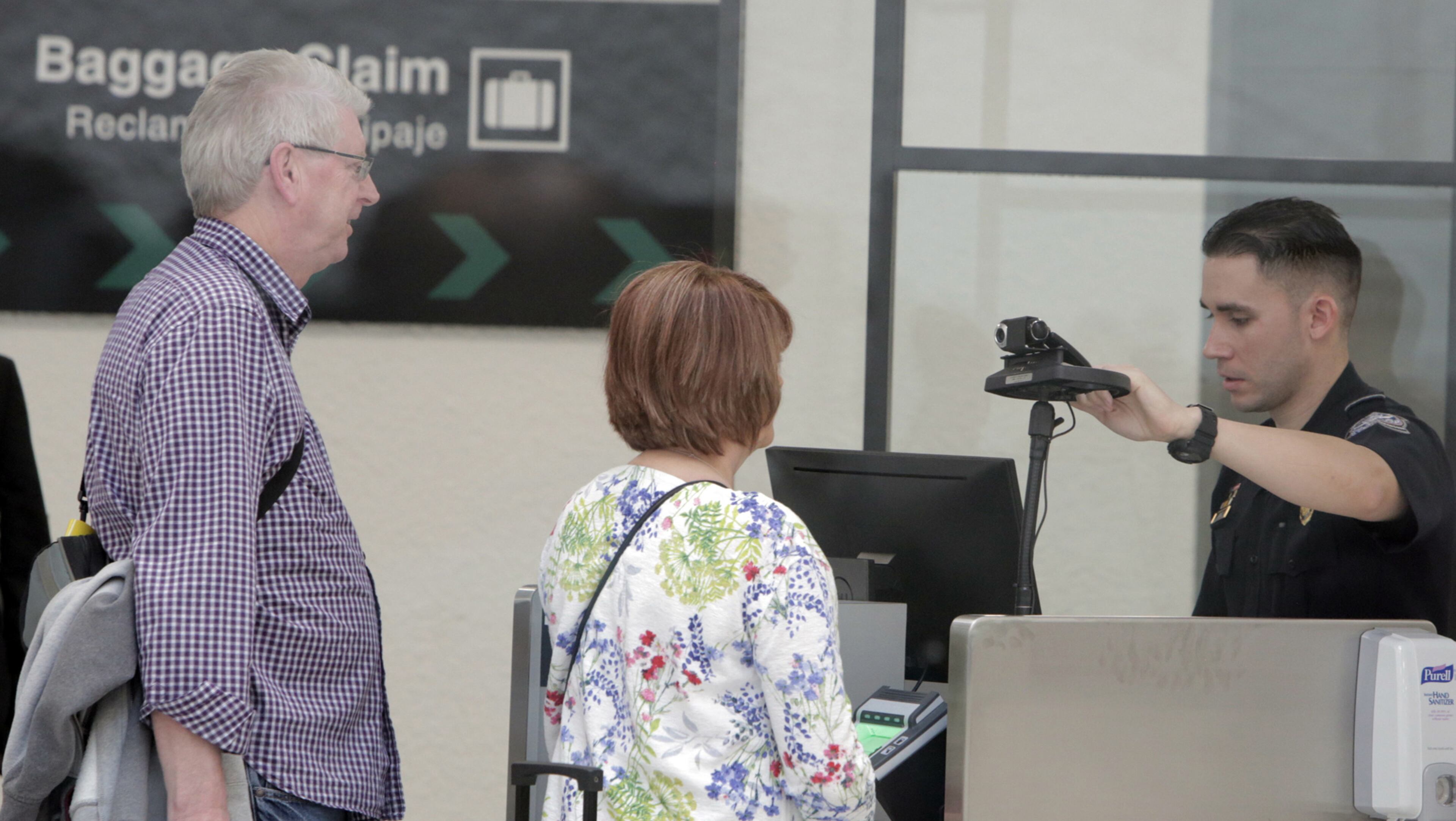 An agent of U.S. Customs and Border Protection prepares to use the new facial recognition technology on newly arrived passengers to Miami International Airport on Feb 27, 2018. (Jose A. Iglesias/Miami Herald/TNS)