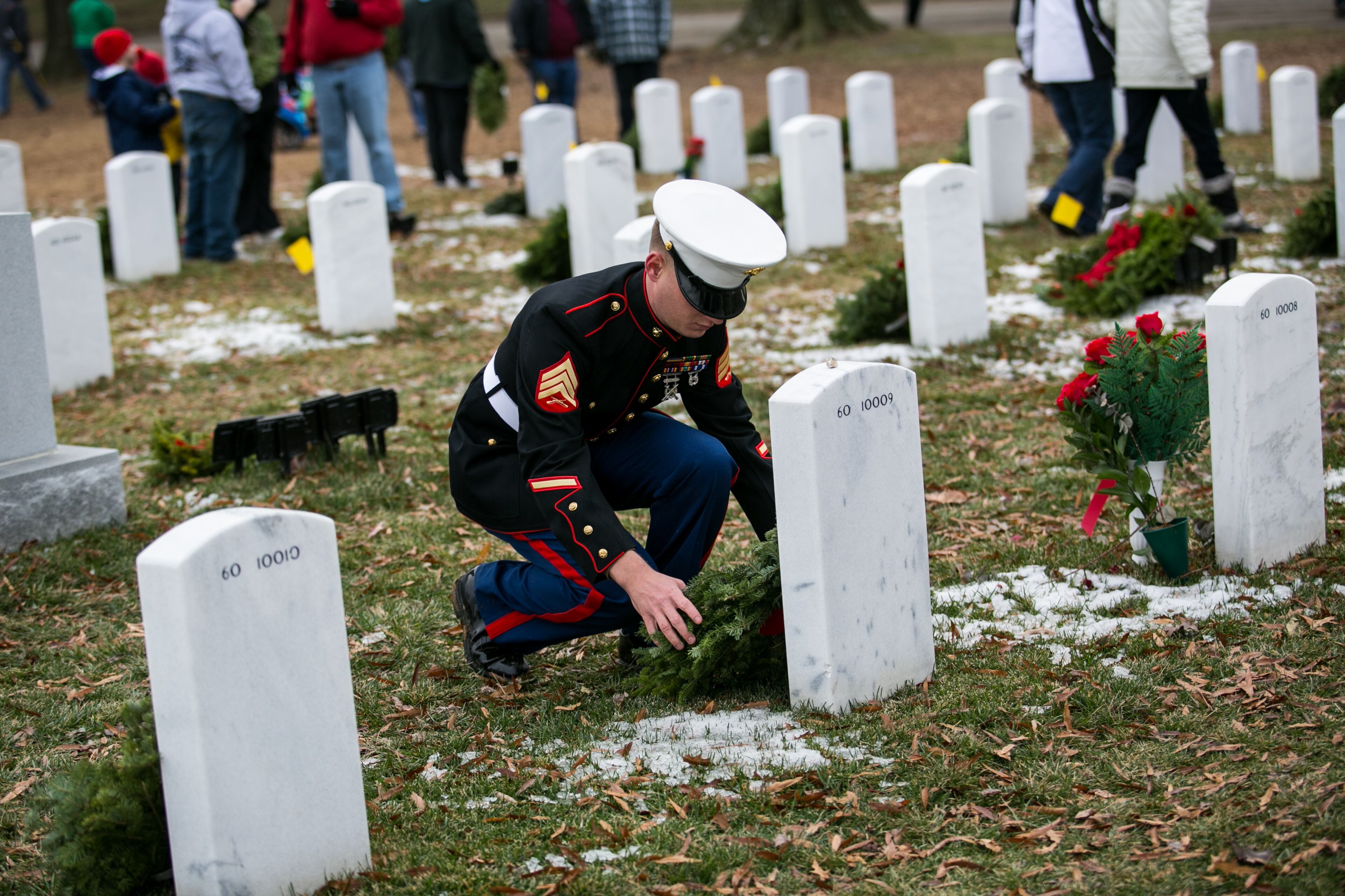 ARLINGTON, VA - DECEMBER 14: Marine Sgt. James Kledzik lays a wreath at the headstone of Air Force Airman 1st Class Matthew R. Seidler, in Section 60 of Arlington National Cemetery, December 14, 2013 in Arlington, Virginia. Seidler was killed January 5, 2012 at Camp Bastion, Afghanistan, of injuries suffered when his vehicle struck an improvised explosive device. Volunteers and families of the fallen placed thousands of remembrance wreaths on headstones throughout the cemetery on National Wreaths Across America Day. (Photo by Drew Angerer/Getty Images)