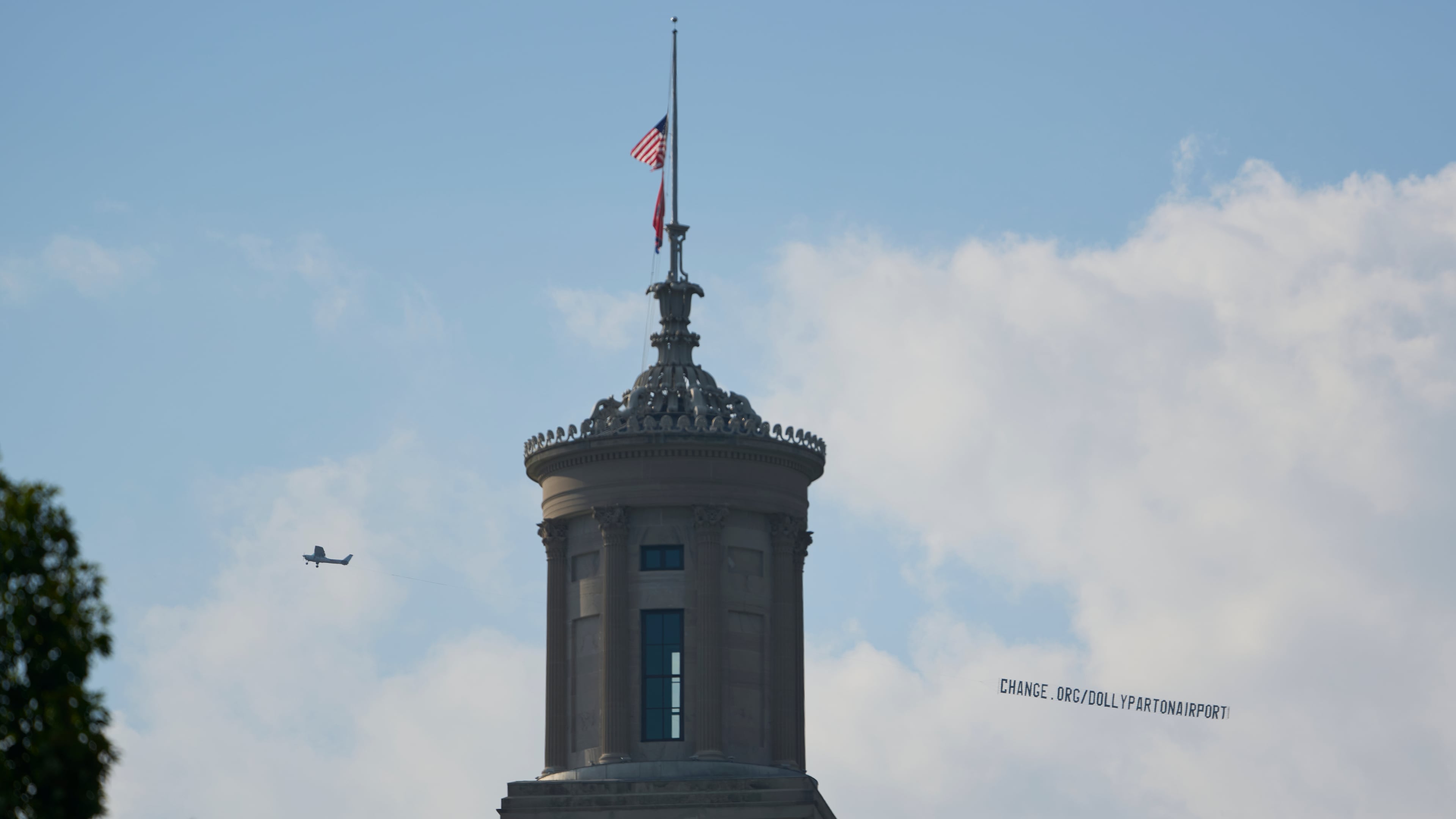 A plane flies over Nashville, Tenn., towing a banner reading “change.org/DollyPartonAirport” as part of an effort to rename the airport after Dolly Parton, Friday, Aug. 28, 2026. (AP Photo/George Walker IV)