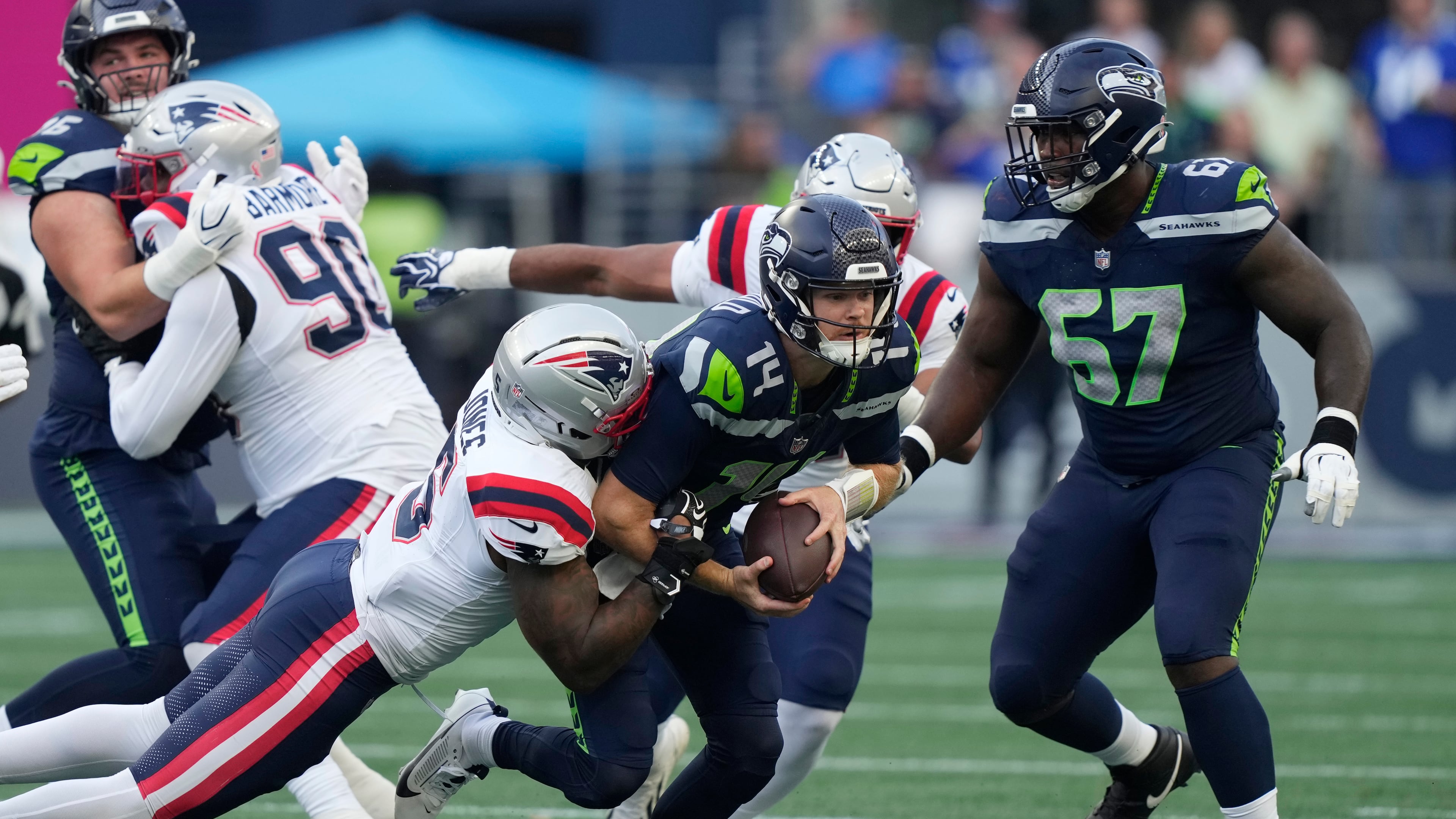 Seattle Seahawks quarterback Sam Darnold, center, is sacked by New England Patriots linebacker Dre'mont Jones, left, as Seattle Seahawks linebacker Connor O'Toole is at right, during the first half of an NFL football game, Wednesday, Sept. 9, 2026, in Seattle. (AP Photo/Stephen Brashear)