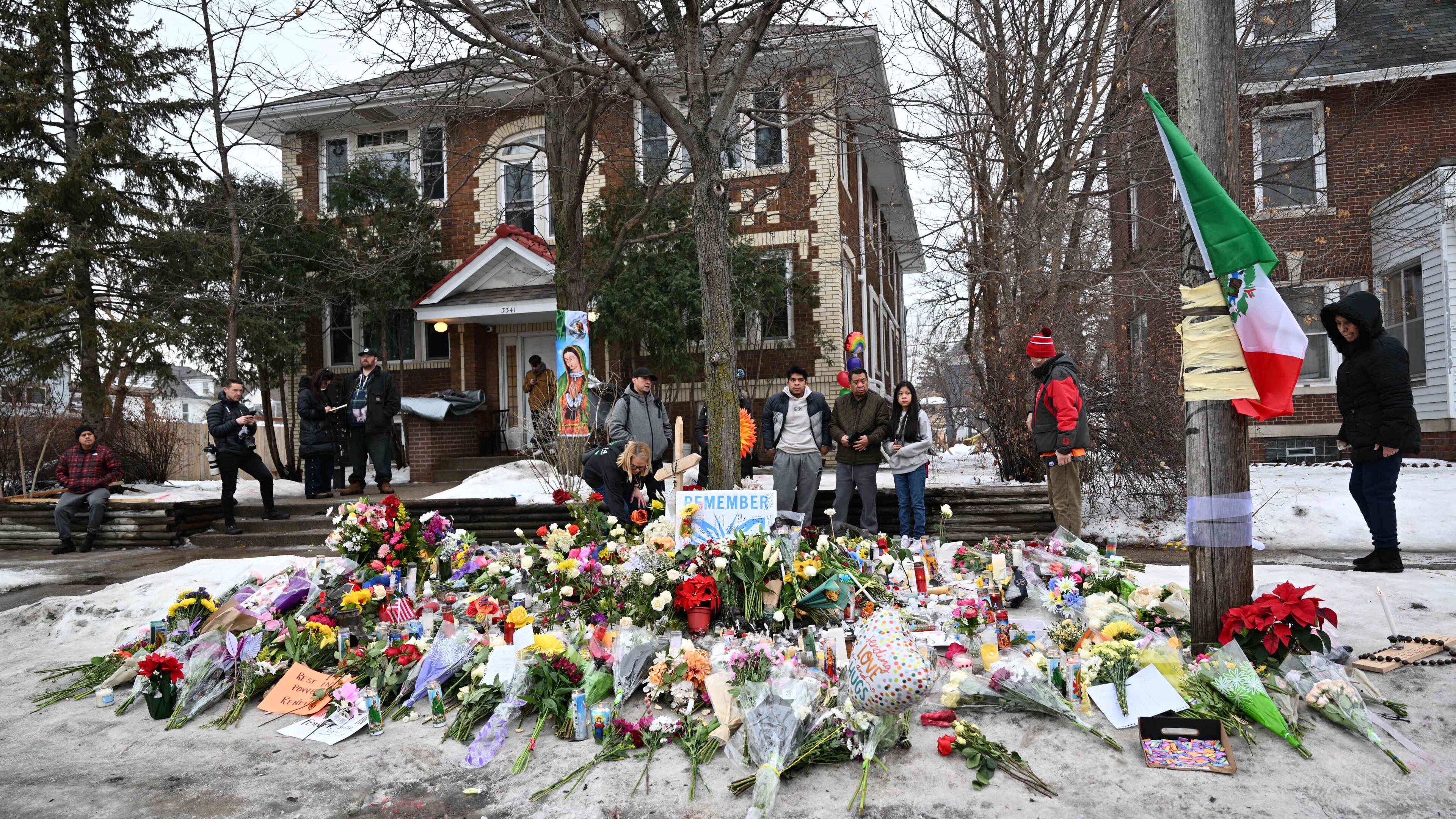 People gather around a makeshift memorial honoring Renee Good who was fatally shot by a federal law enforcement agent near the site of the shooting in Minneapolis, Thursday, Jan. 8, 2026. (AP Photo/Tom Baker)