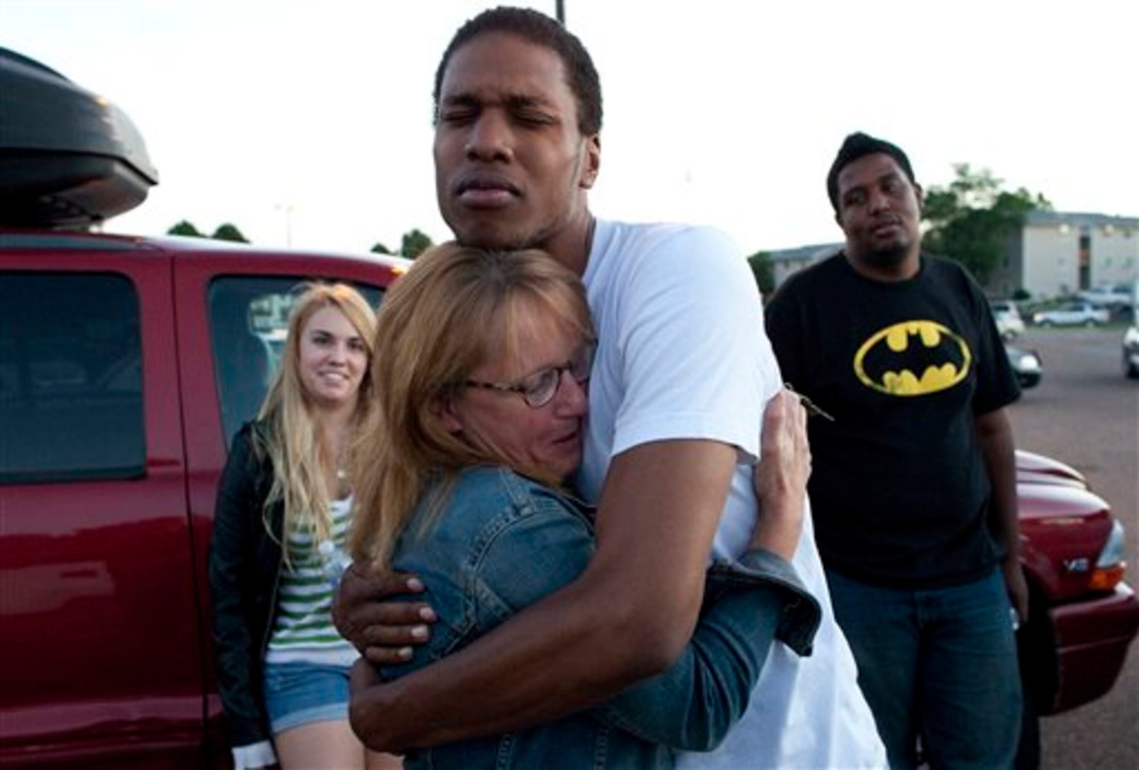 Judy Goos, second from left, hugs her daughters friend, Isaiah Bow, 20, while eye witnesses Emma Goos, 19, left, and Terrell Wallin, 20, right, gather outside Gateway High School where witness were brought for questioning Friday, July 20, 2012 in Denver. A gunman wearing a gas mask set off an unknown gas and fired into a crowded movie theater at a midnight opening of the Batman movie "The Dark Knight Rises," killing at least 12 people and injuring at least 50 others, authorities said. (AP Photo/Barry Gutierrez)