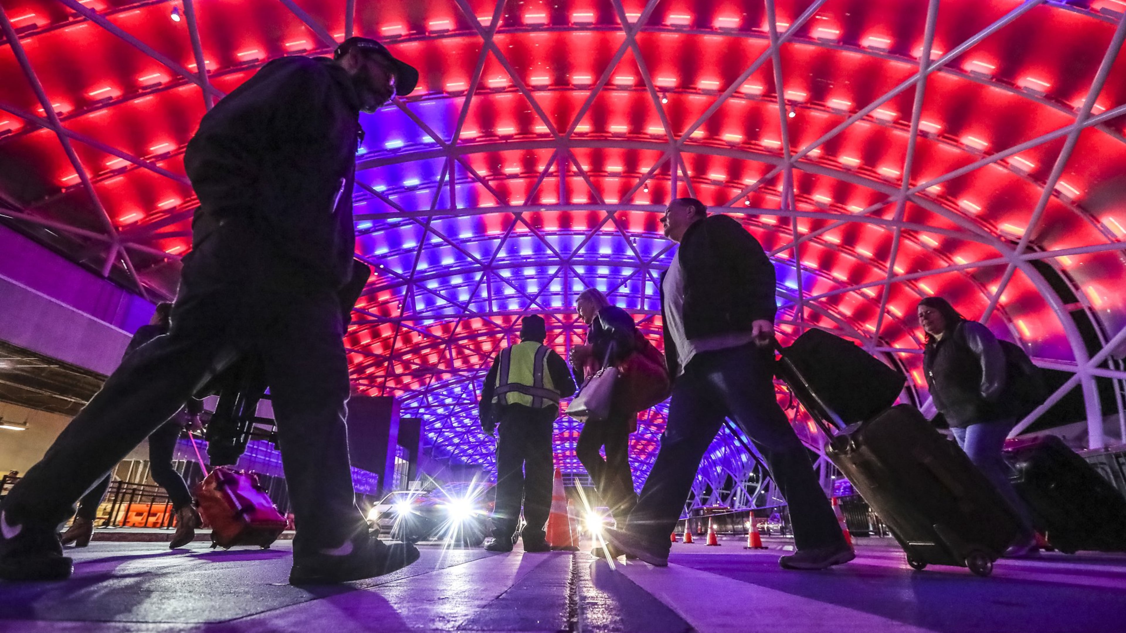 Under Super Bowl colors passengers travel under the illuminated canopy on the North Terminal at Hartsfield-Jackson International Airport that was bustling with passengers arriving for the Super Bowl Friday, Feb. 1, 2019 and airport officials are ramping up operations for even heavier traffic to come. JOHN SPINK/JSPINK@AJC.COM