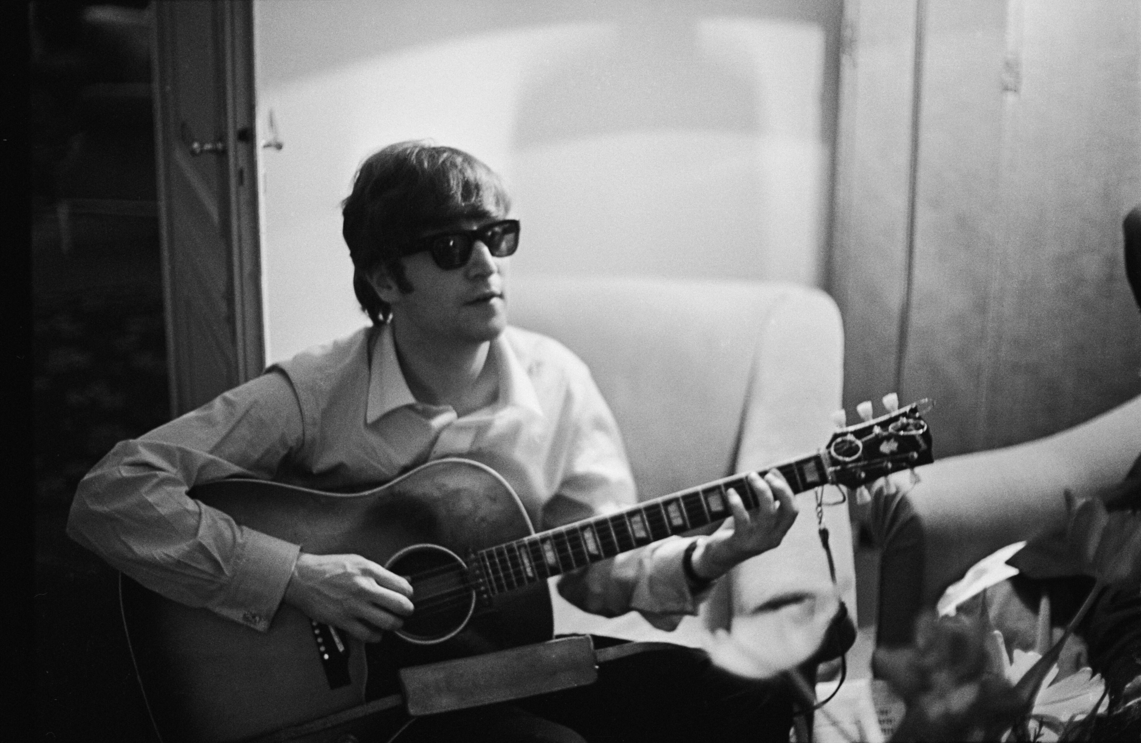 John Lennon (1940-1980) of the Beatles plays the guitar in a hotel room in Paris on Jan. 16, 1964.
