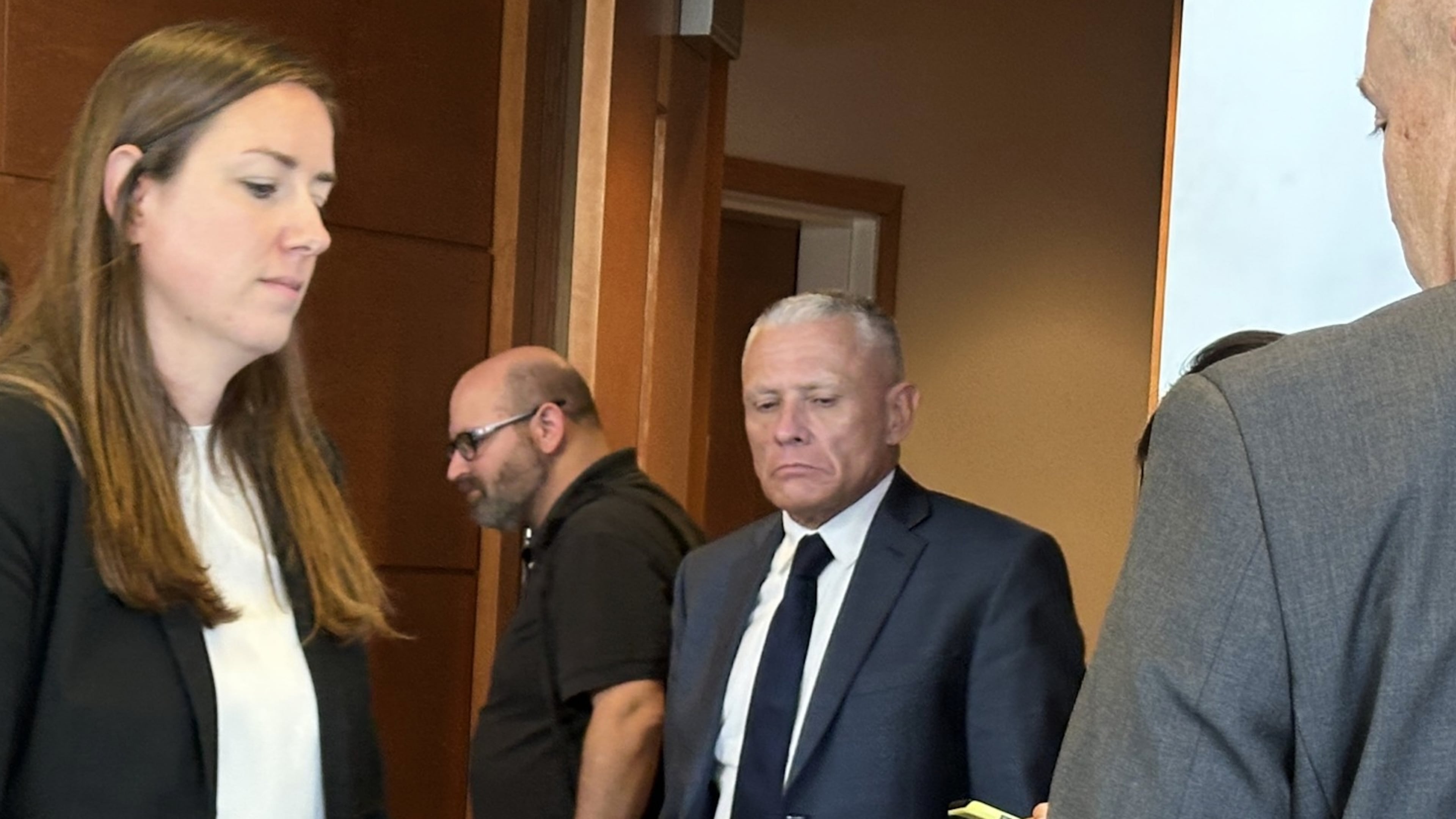 This photo taken with a smartphone shows defense attorney Delia McCarthy, left, and Jeffrey Buskey, center, charged with multiple counts of aggravated felonious sexual assault, leaving a courtroom during a break in Buskey's trial in Manchester, N.H., Monday, Sept. 14, 2026. (AP Photo/Holly Ramer)