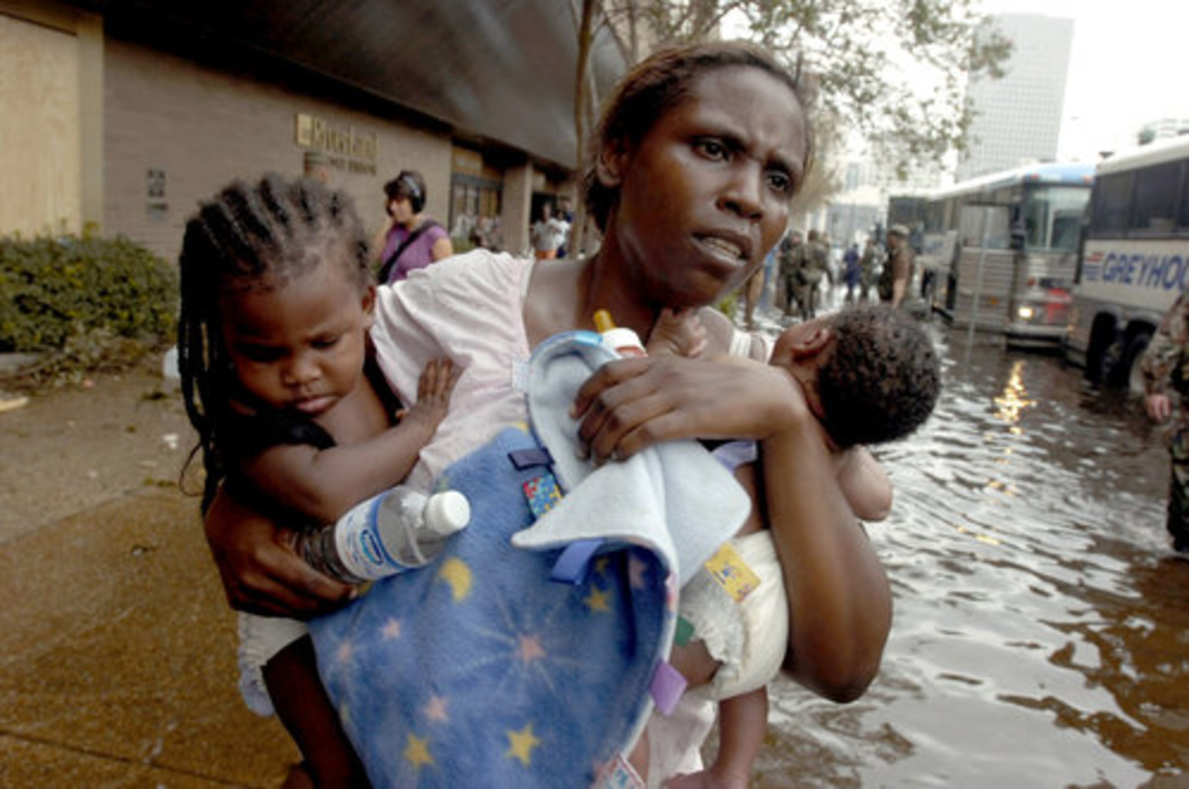 A Hurricane Katrina survivor and her two babies wade through the water out to a waiting chartered bus outside the Hyatt Regency Hotel in New Orleans, Thursday, Sept.1, 2005. Starting with an estimated 16,000-20,000 people and estimated to continue through the night, refugees were walked through the lower level of the hotel to the awaiting air-conditioned buses.