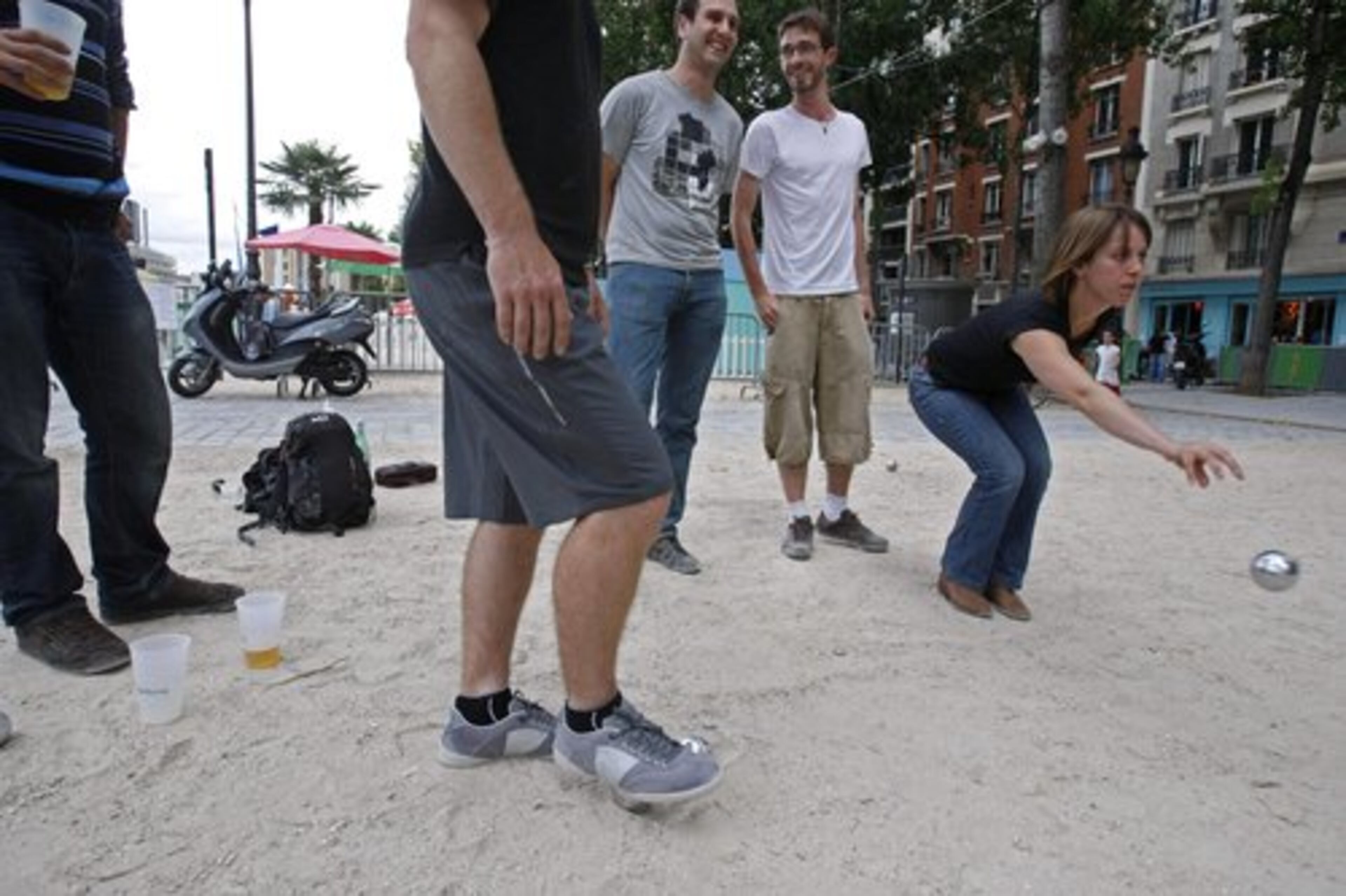 A Parisian tosses a metal ball as she plays the game of petanque with her friends in Paris.