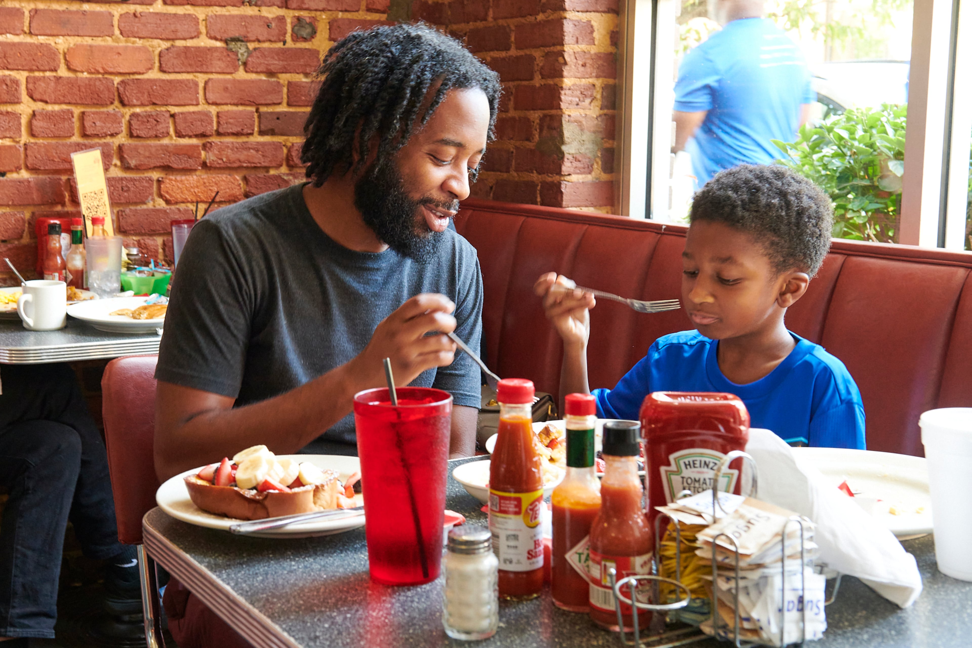 Julian McDaniel and son Landon eat waffles topped with strawberries at Thumbs Up Diner in Atlanta. (Greg Rannells for The Atlanta Journal-Constitution)