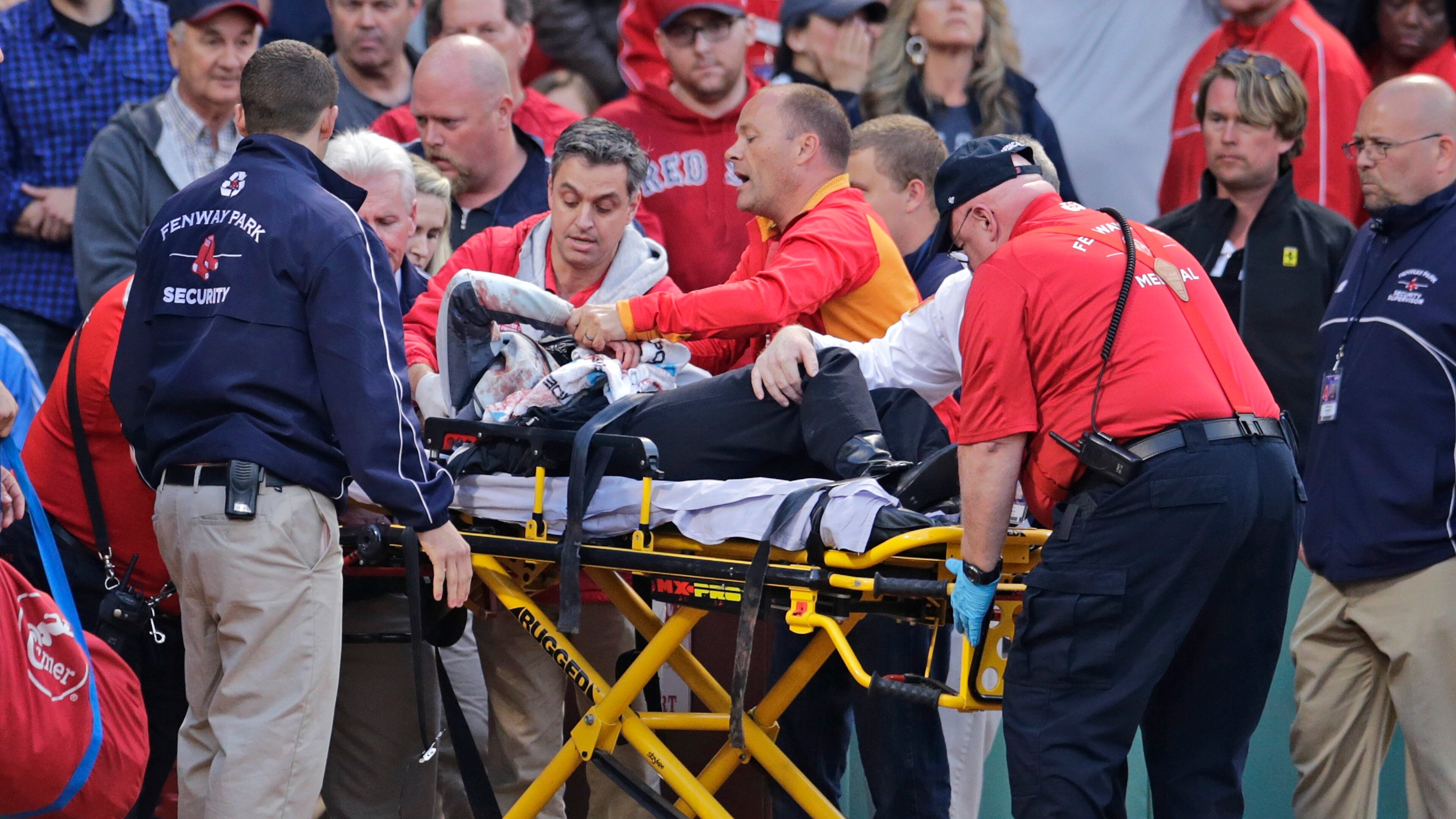 A fan, who was accidentally hit in the head with a broken bat by Oakland Athletics' Brett Lawrie, is helped from the stands during a baseball game against the Boston Red Sox at Fenway Park in Boston on June 5, 2015. The game was stopped while they wheeled her down the first base line.