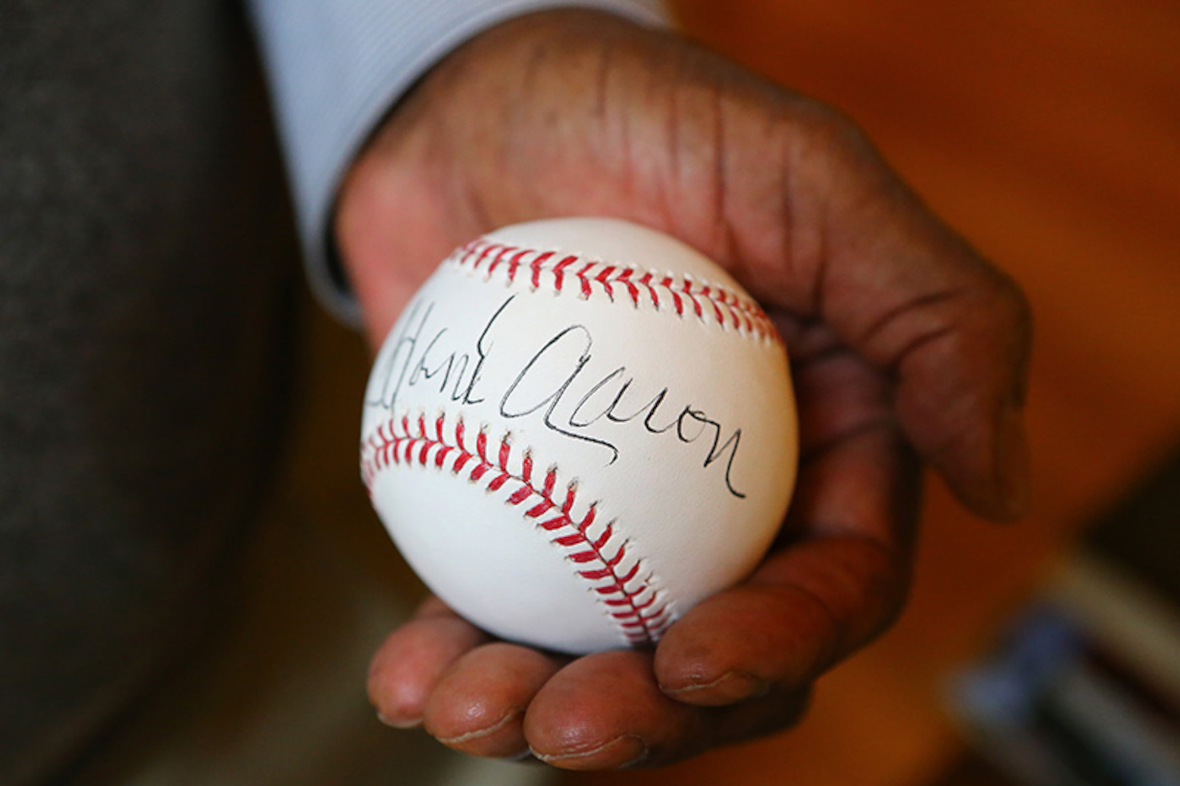 Braves legend Hank Aaron autographs a baseball on the eve of his 80th birthday for the upcoming celebration at his home.