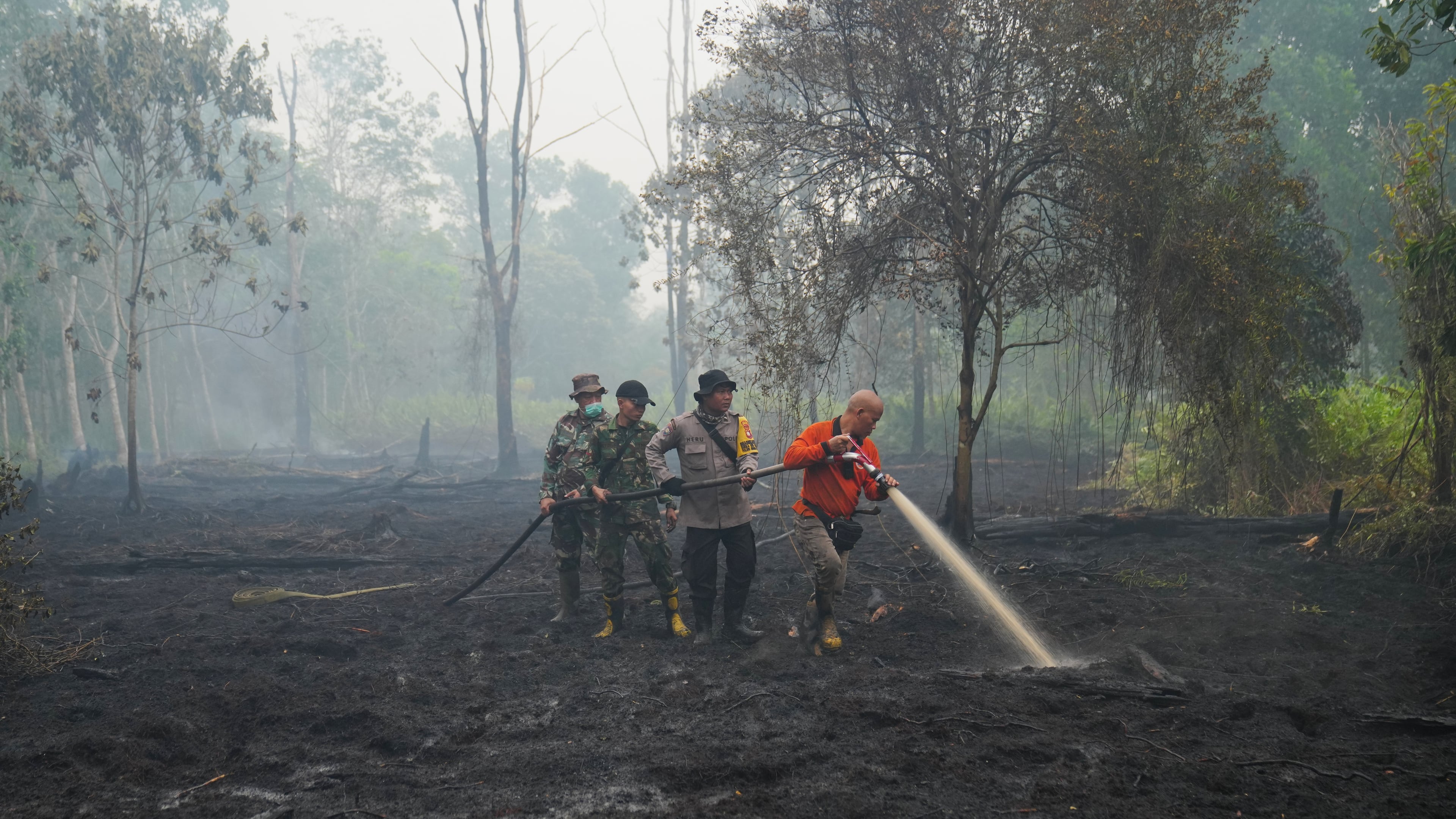 FILE - Firefighters spray water to put out wildfires burning through peatland forest in Kubu Raya, West Kalimantan, Indonesia, Sept. 12, 2026. (AP Photo/Tatan Syuflana, File)