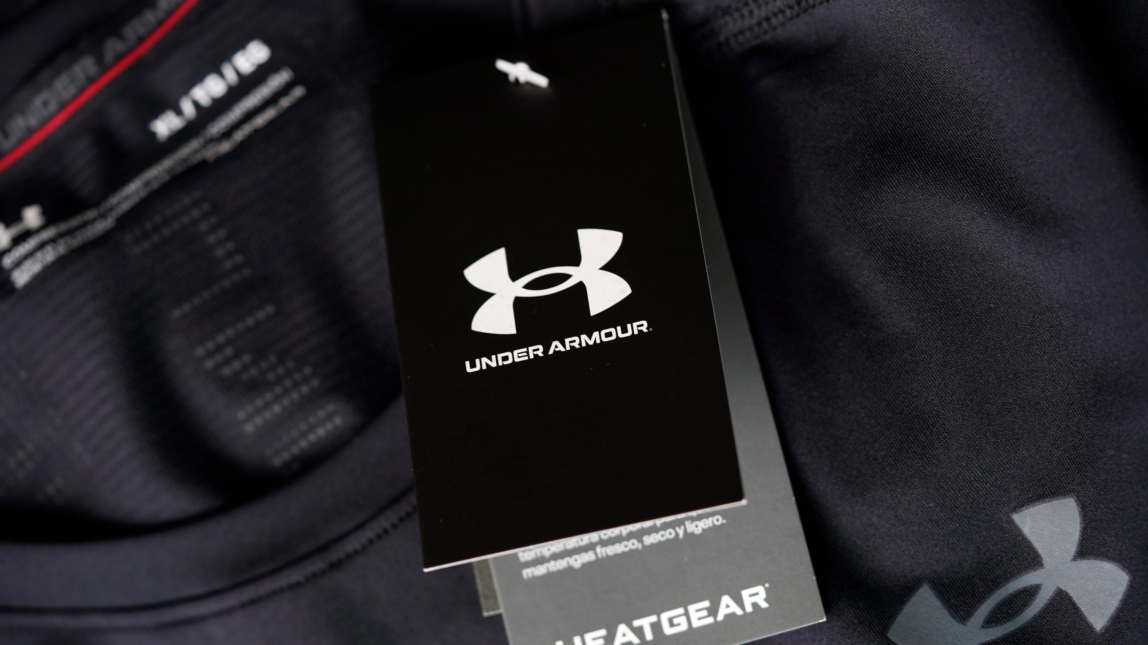 FILE - The company logo graces a sales tag on a compression shirt for sale in an Under Armour store in an outlet mall on May 3, 2021, in Lakewood, Colo. (AP Photo/David Zalubowski, File)