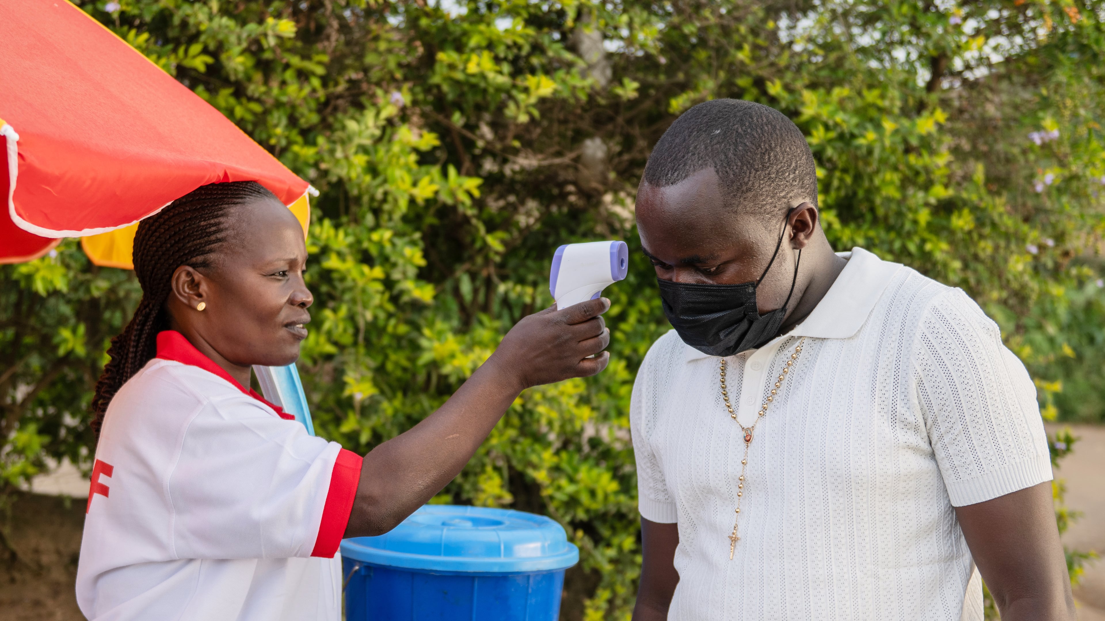 A health worker uses a thermometer to screen a man by the roadside in Bunia, Congo, Tuesday, May 19, 2026. (AP Photo/Moses Sawasawa)