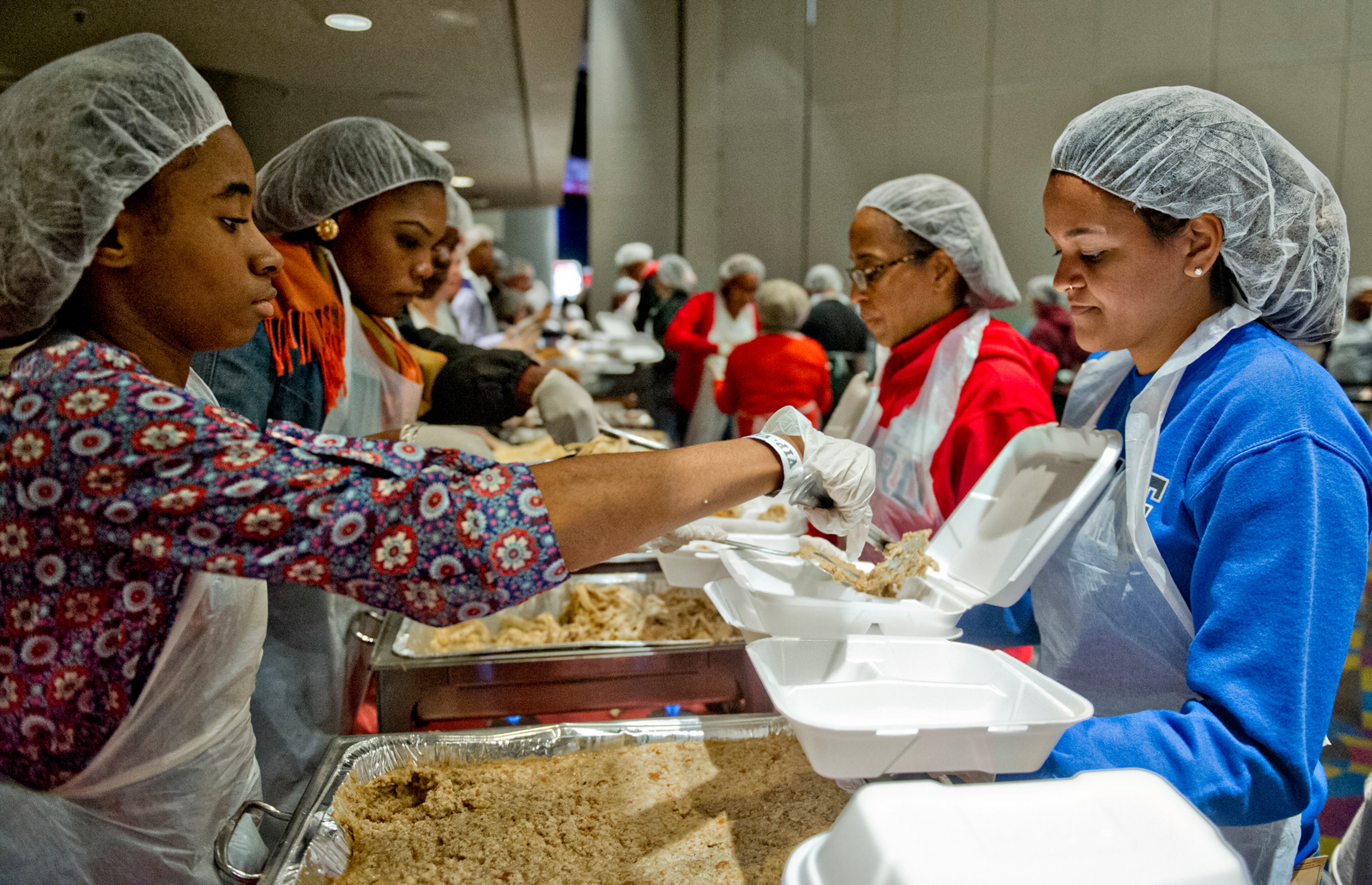 Kameron Austin (left) scoops a helping of stuffing onto a plate held by Allegra George.