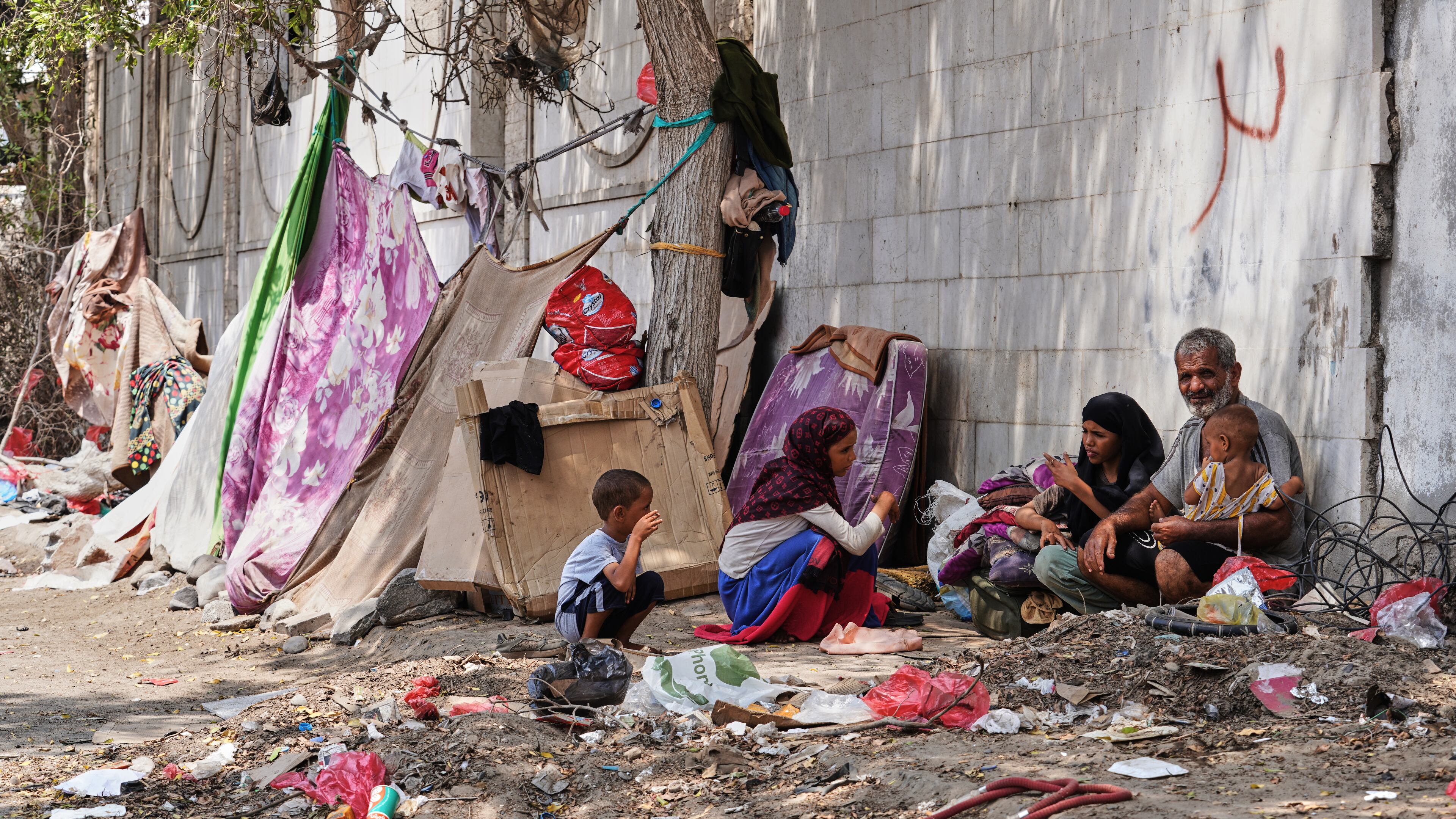 A displaced Yemeni family sits beside a makeshift shelter along a roadside in Aden, Yemen, Sunday, Oct. 11, 2026. (AP Photo/Abdulnasser Alseddik)