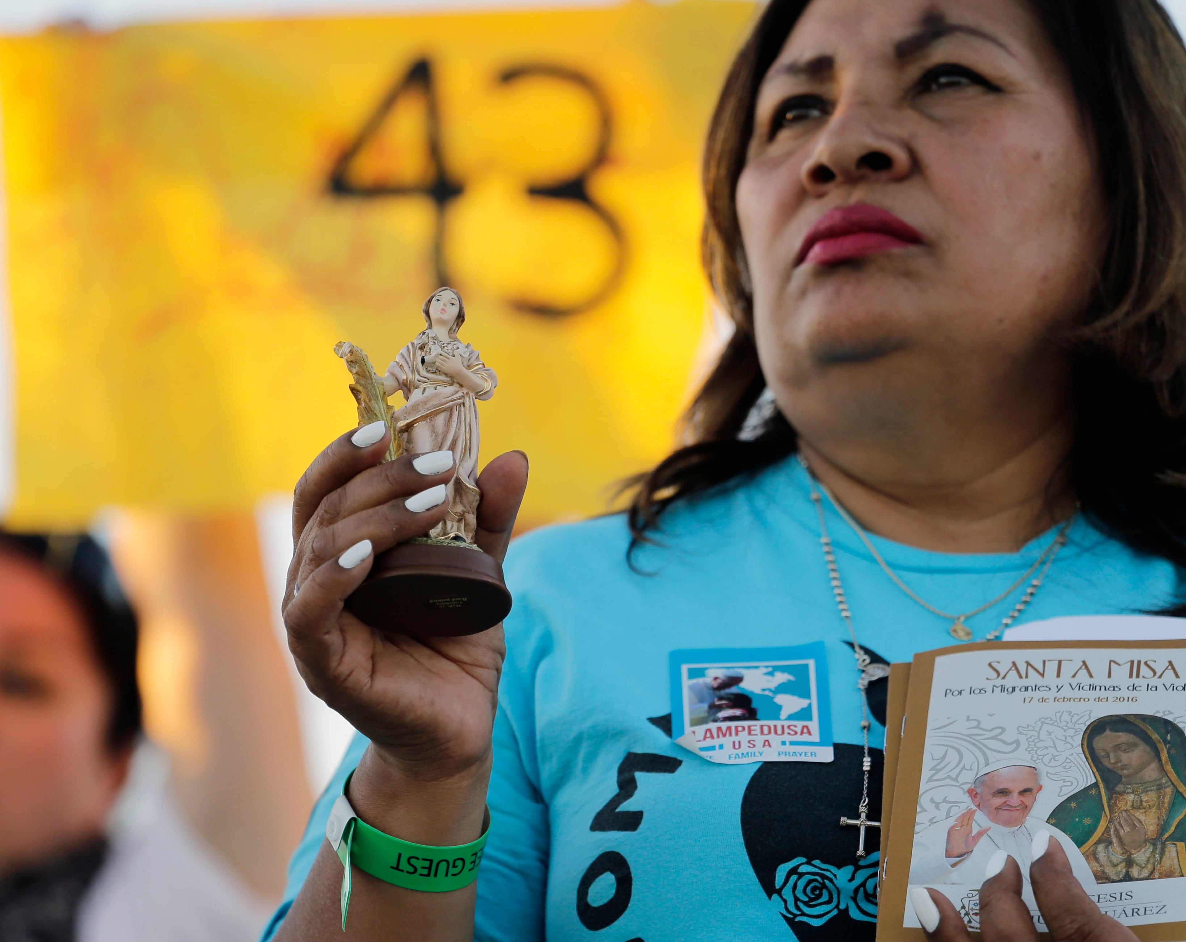 A Catholic woman holds items as she prays while watching Pope Francis' Juarez, Mexico, Mass from a levee along the banks of the Rio Grande in El Paso, Texas, Wednesday, Feb. 17, 2016. (AP Photo/Eric Gay)