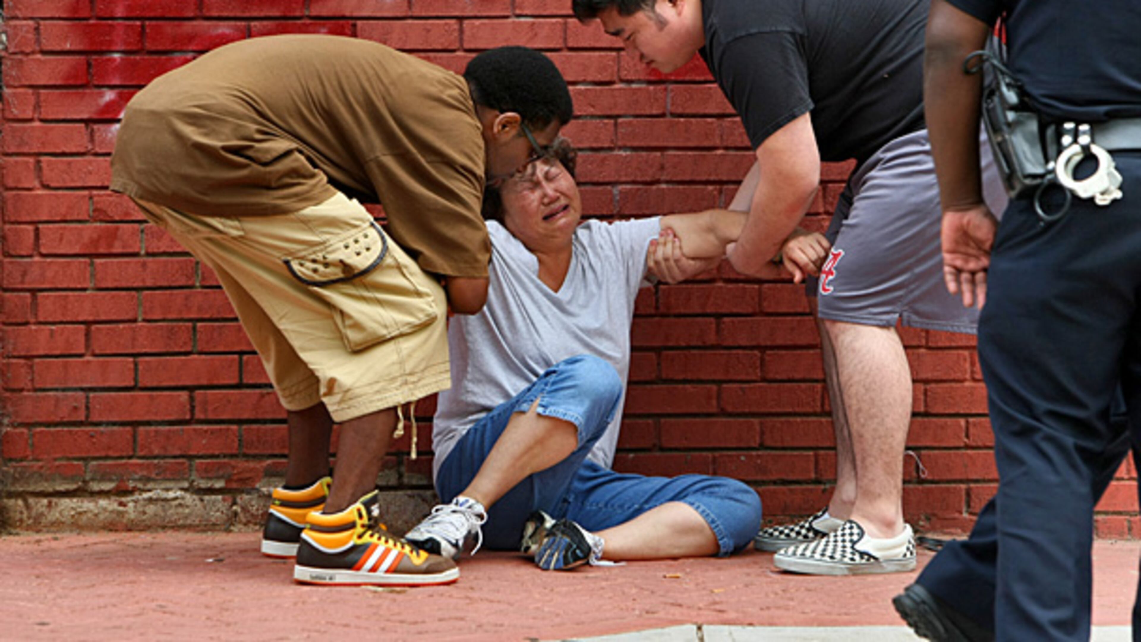 Michael Seagrave (left) and James Sung (right) help a grieving Chae Sung to her feet after she arrived at the store where her husband was killed in 2010. JOHN SPINK / JSPINK@AJC.COM