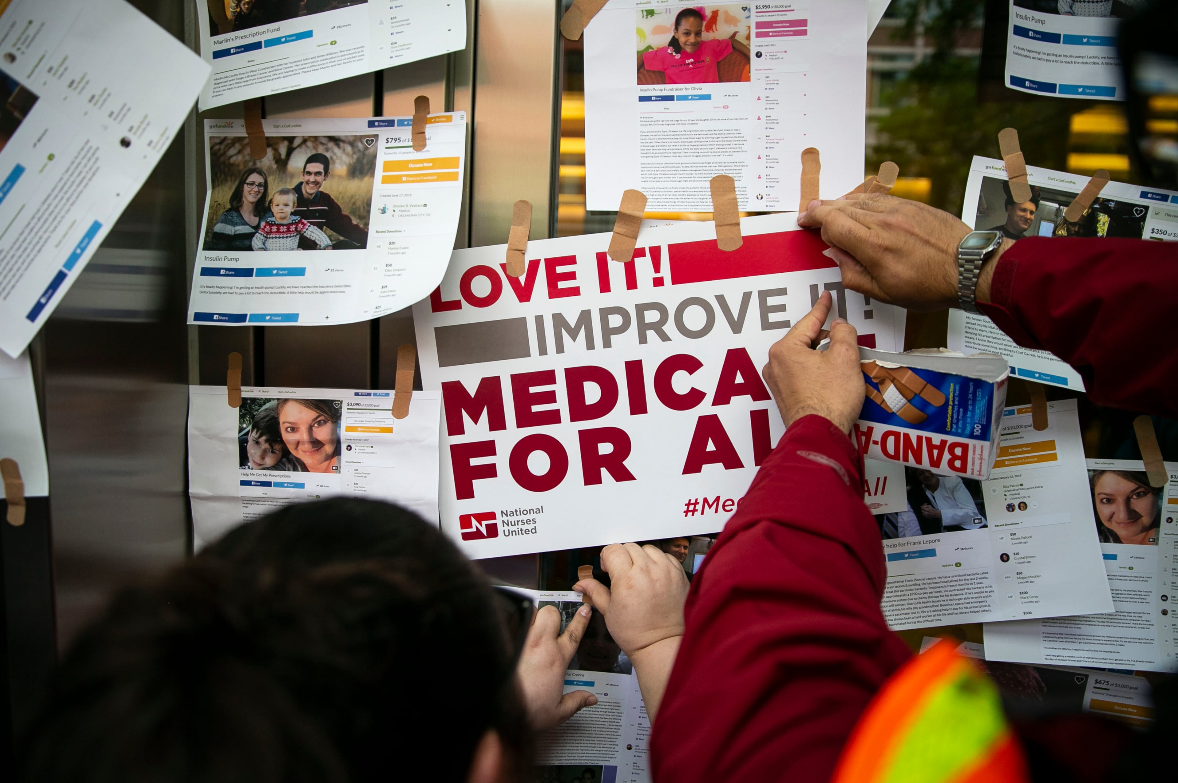 Examples of GoFundMe pages for patients who used crowdfunding to cover medical expenses are posted on doors for the headquarters of Pharmaceutical Research and Manufacturers of America during a “Medicare for All” rally in Washington, April 29, 2019. (Al Drago/The New York Times)