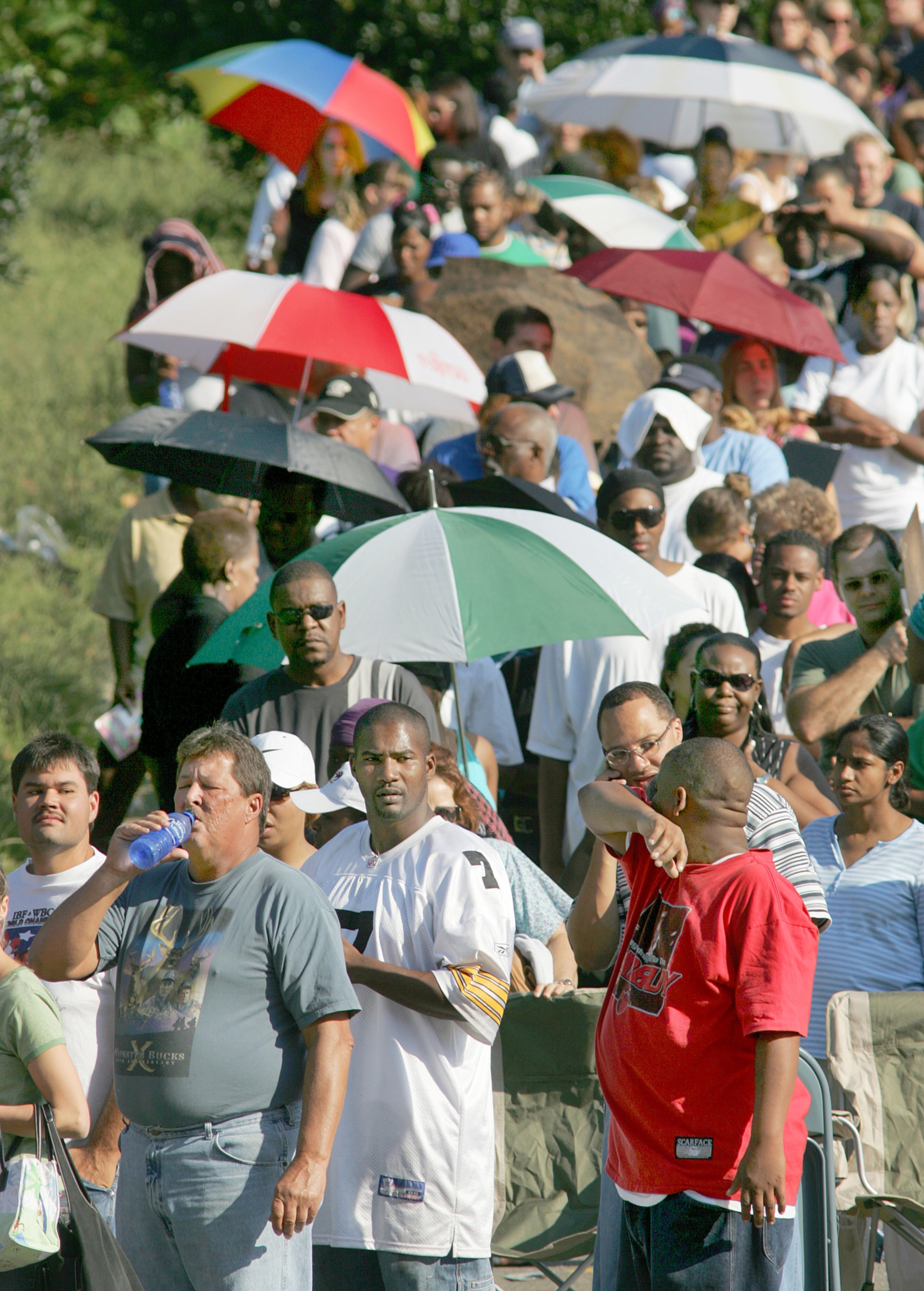 050909 - MARIETTA/COBB COUNTY - Left to right: Donald Collins Sr. (drinking water) from St. Bernard parish, Delano Essue and Evan Jones (all-cq) from New Orleans bear the sun as they wait Friday, September 9, 2005. Hundreds of evacuees showed up overnight to be first in line at Life University in Marietta early Friday morning. Life is one of three centers in the Atlanta metro area serving the needs of the hurricane evacuees. (JOHN SPINK/AJC staff)