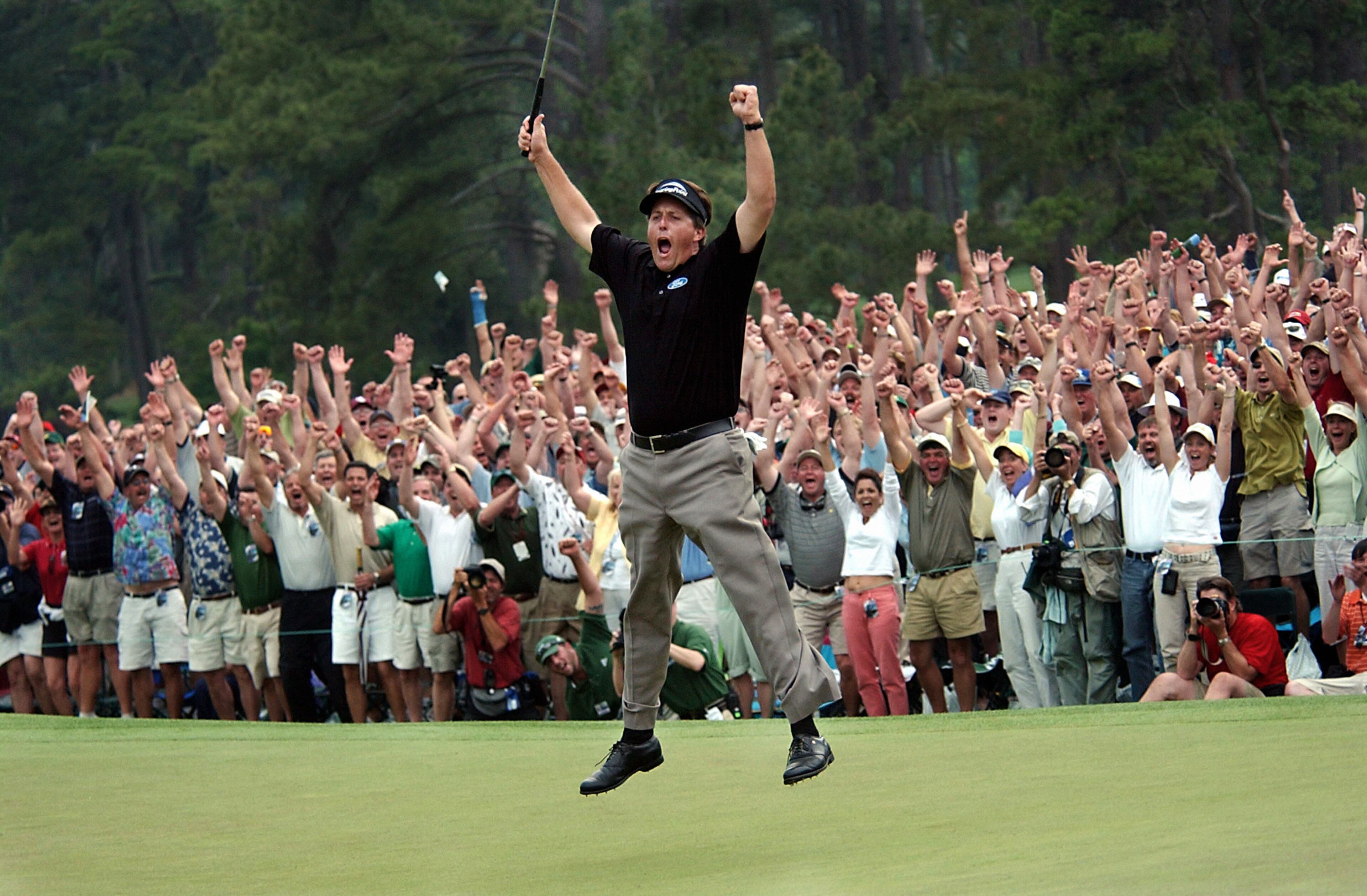 In this April 11, 2004, file photo, taken by Dave Martin, Phil Mickelson celebrates after winning the Masters golf tournament with at the Augusta National Golf Club in Augusta, Ga. Martin, a longtime Associated Press photographer based in Montgomery, Ala., died after collapsing on the Georgia Dome field at the Chick-fil-A Bowl on Tuesday, Dec. 31, 2013. Martin was 59.(AP Photo/Dave Martin, File)