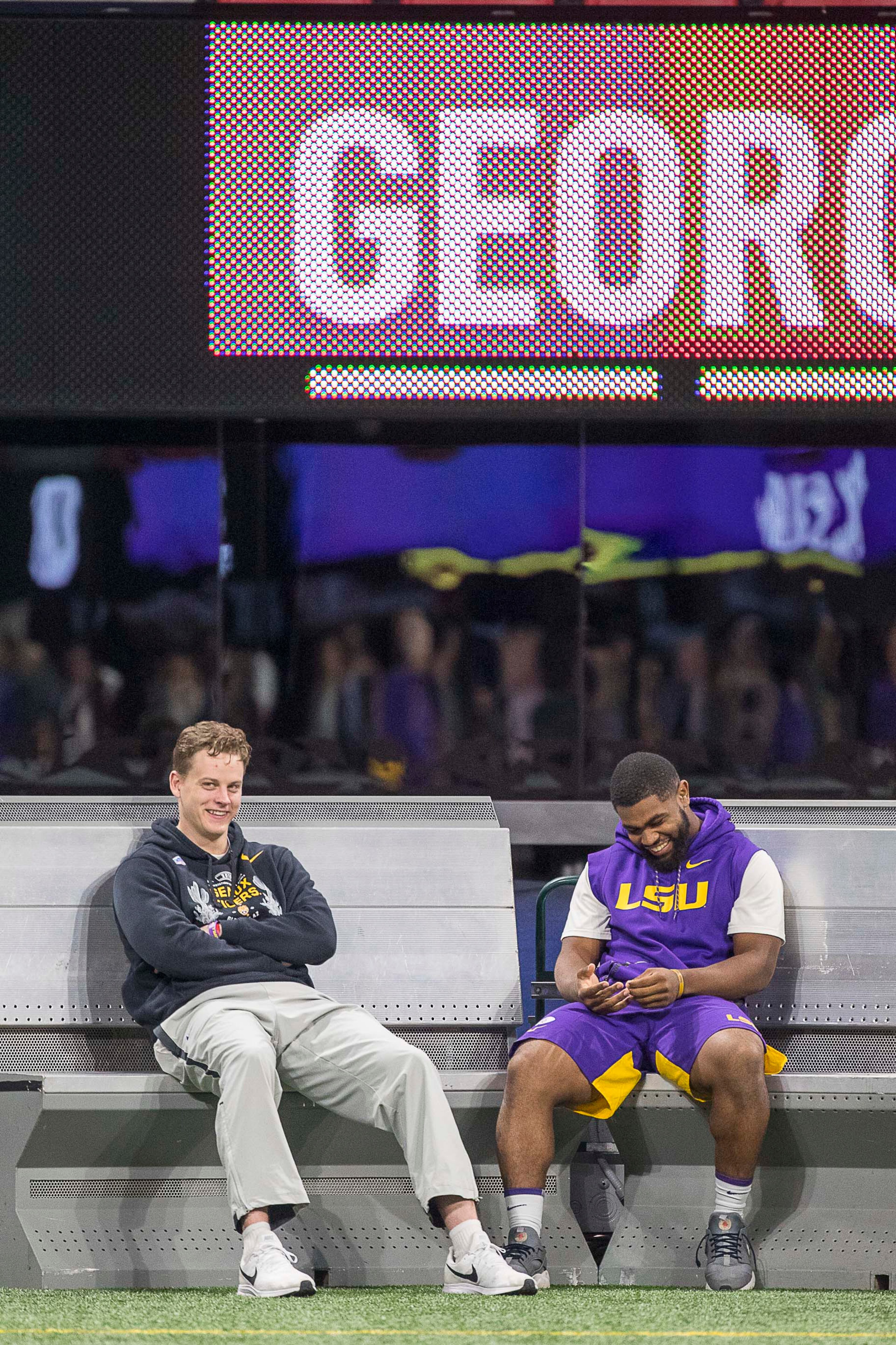 LSU quarterback Joe Burrow (left) sits on the bench while his teammates take the field during their practice time at Mercedes-Benz Stadium in Atlanta, Friday, December 6, 2019. The Louisiana State University Tigers take on the University of Georgia Bulldogs during the SEC Championship game on Saturday. (ALYSSA POINTER/ALYSSA.POINTER@AJC.COM)
