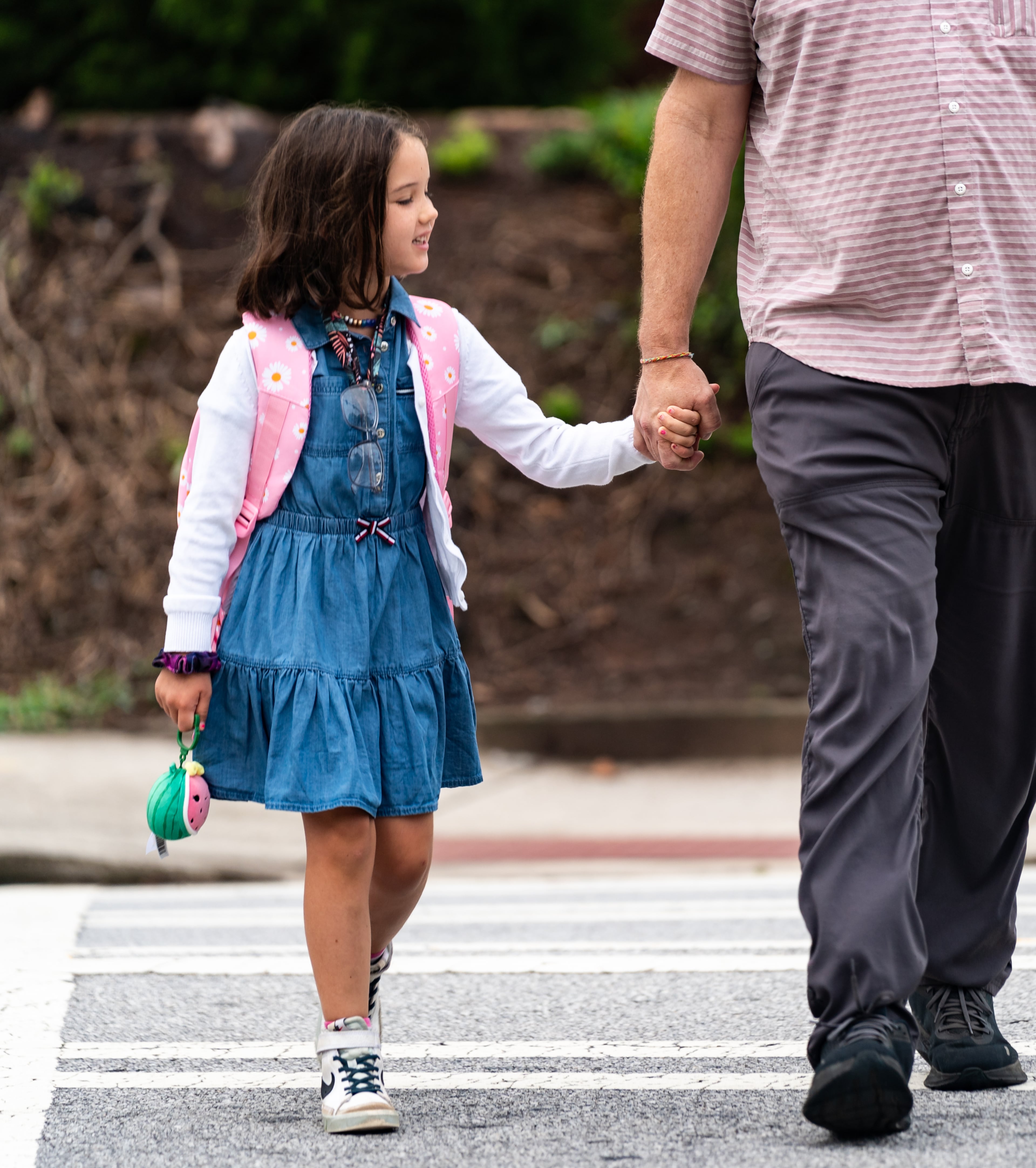 Olivia Lewis, 6, crosses the street with her father Jeremy Lewis before her first day of first grade at Glennwood Elementary School in Decatur on Tuesday, July 30, 2024. (Seeger Gray / AJC)