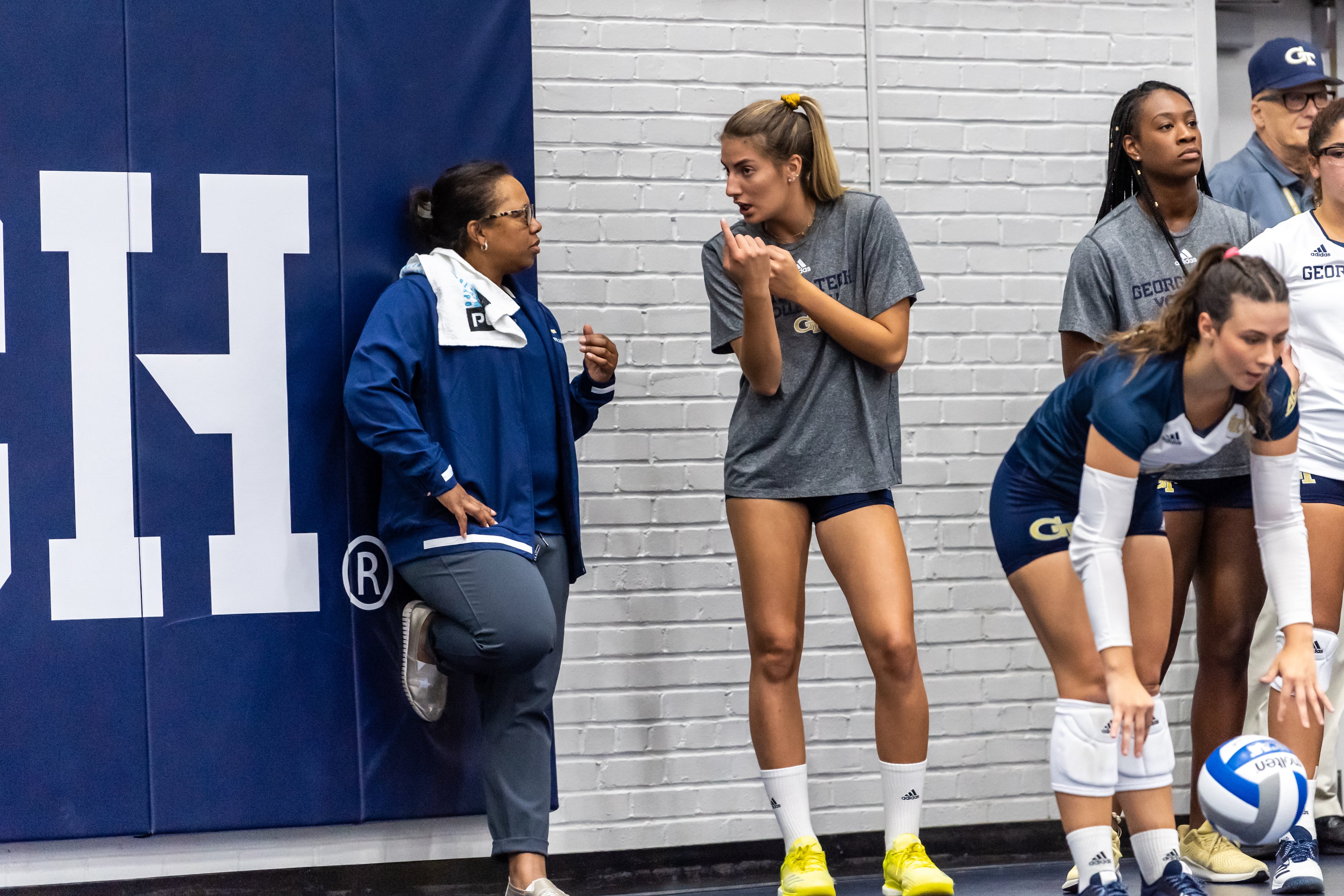 Georgia Tech sports medicine director Carla Gilson (lefft) speaks with Yellow Jackets volleyball player Mariana Brambilla at an August 2019 match at Tech's O'Keefe Gymnasium. (Danny Karnik/Georgia Tech Athletics)
