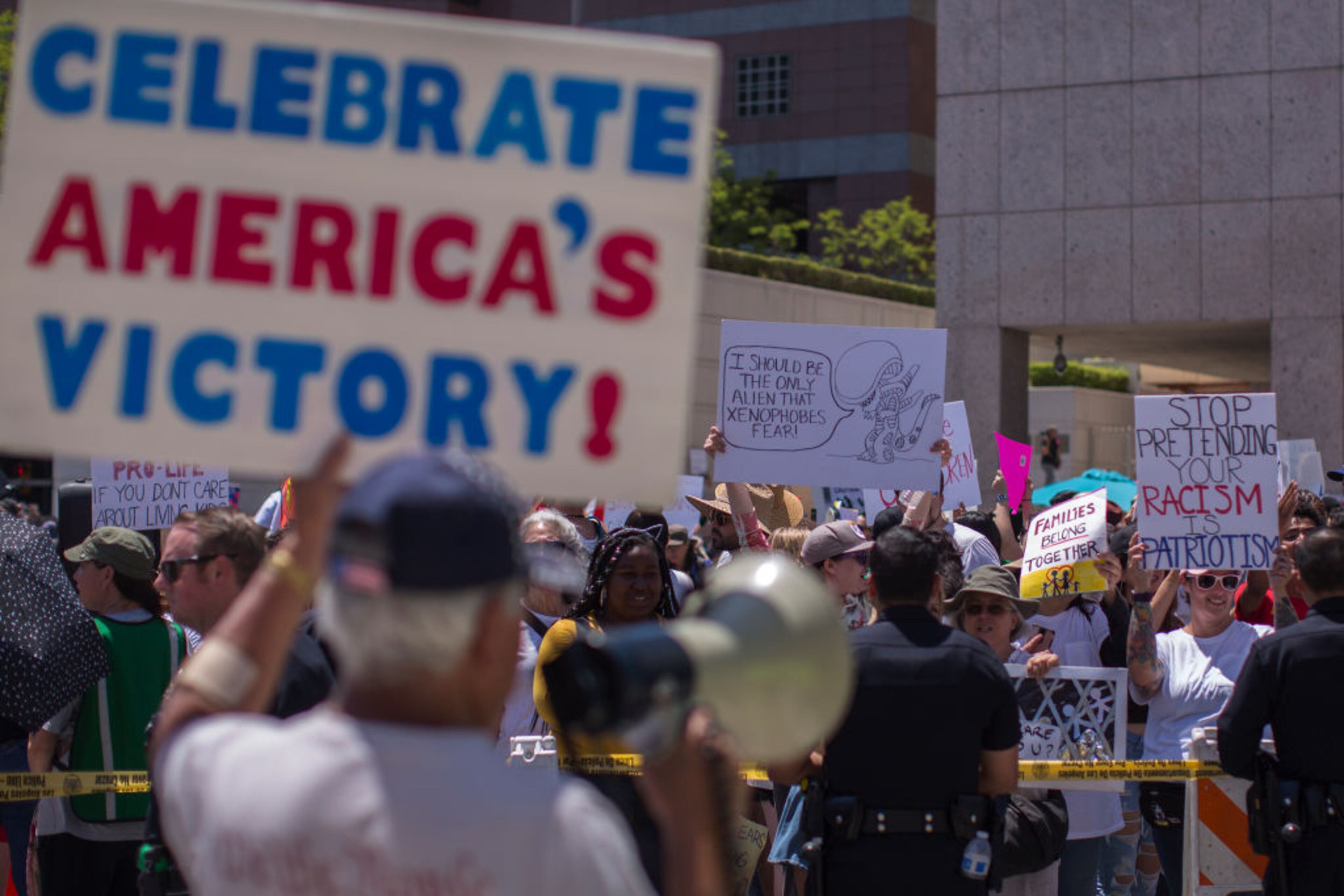LOS ANGELES, CA - JUNE 30: A pro-Trump counter demonstrator holds a sign toward protesters decrying Trump administration immigration and refugee policies on June 30, 2018 in Los Angeles, California. Although President Trump was forced to reverse his policy of removing all children from their immigrant or asylum-seeking parents, little clarity appears to be seen as to how agencies can fulfill a court order to reunite thousands of children and parents detained far apart by multiple agencies. Yesterday, the Justice Department filed papers in a Los Angeles federal court to have families arrested for illegal border crossings incarcerated together indefinitely. The rally is one of more than 700 such protests being held throughout the nation. (Photo by David McNew/Getty Images)
