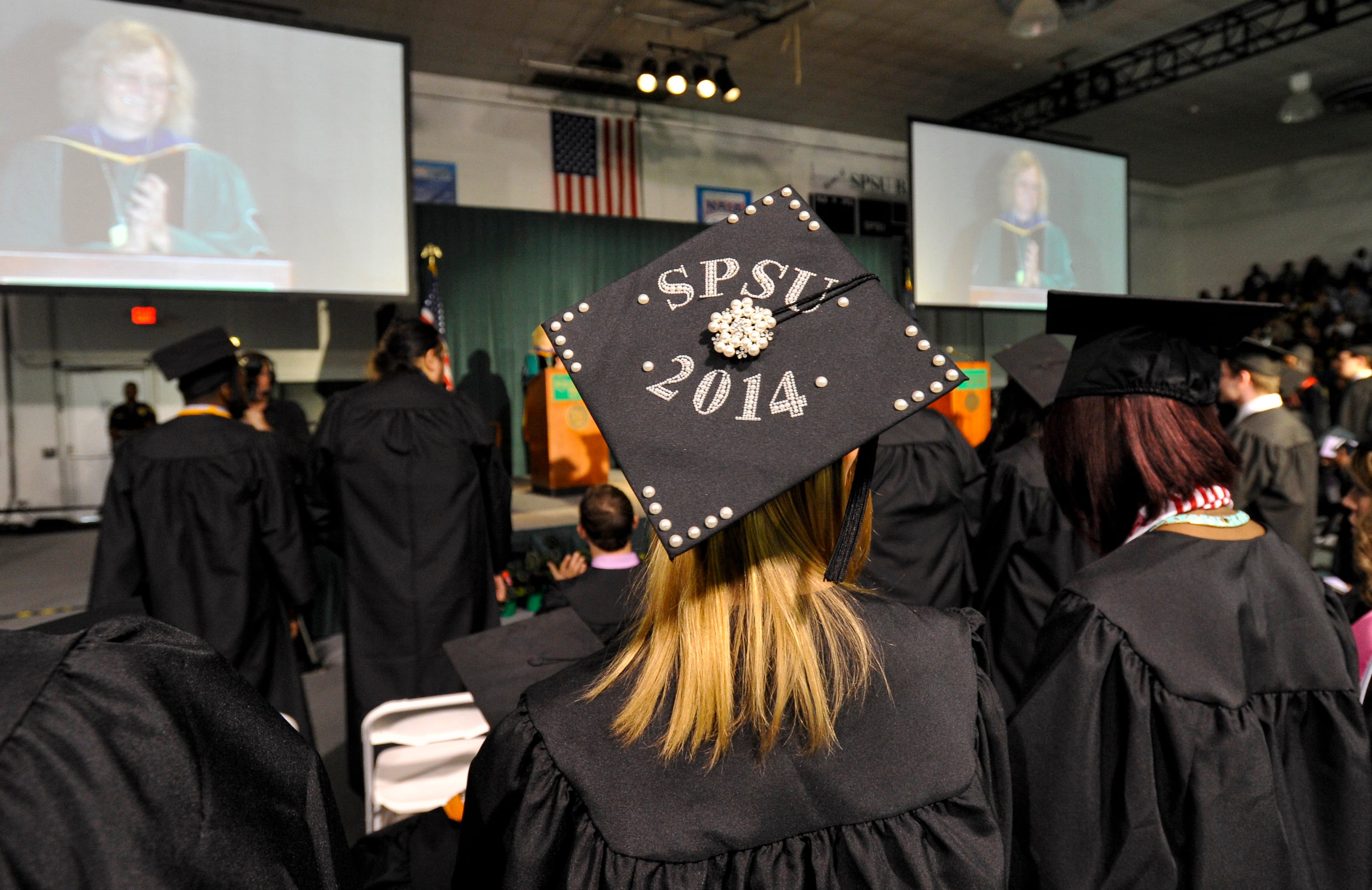 Southern Polytechnic State University president Lisa Rossbacher is shown on large monitors as the college holds its 109th spring commencement, which is also the last spring commencement before SPSU merges with Kennesaw State University next year, on Saturday, May 10, 2014, in Marietta, Ga. David Tulis / AJC Special