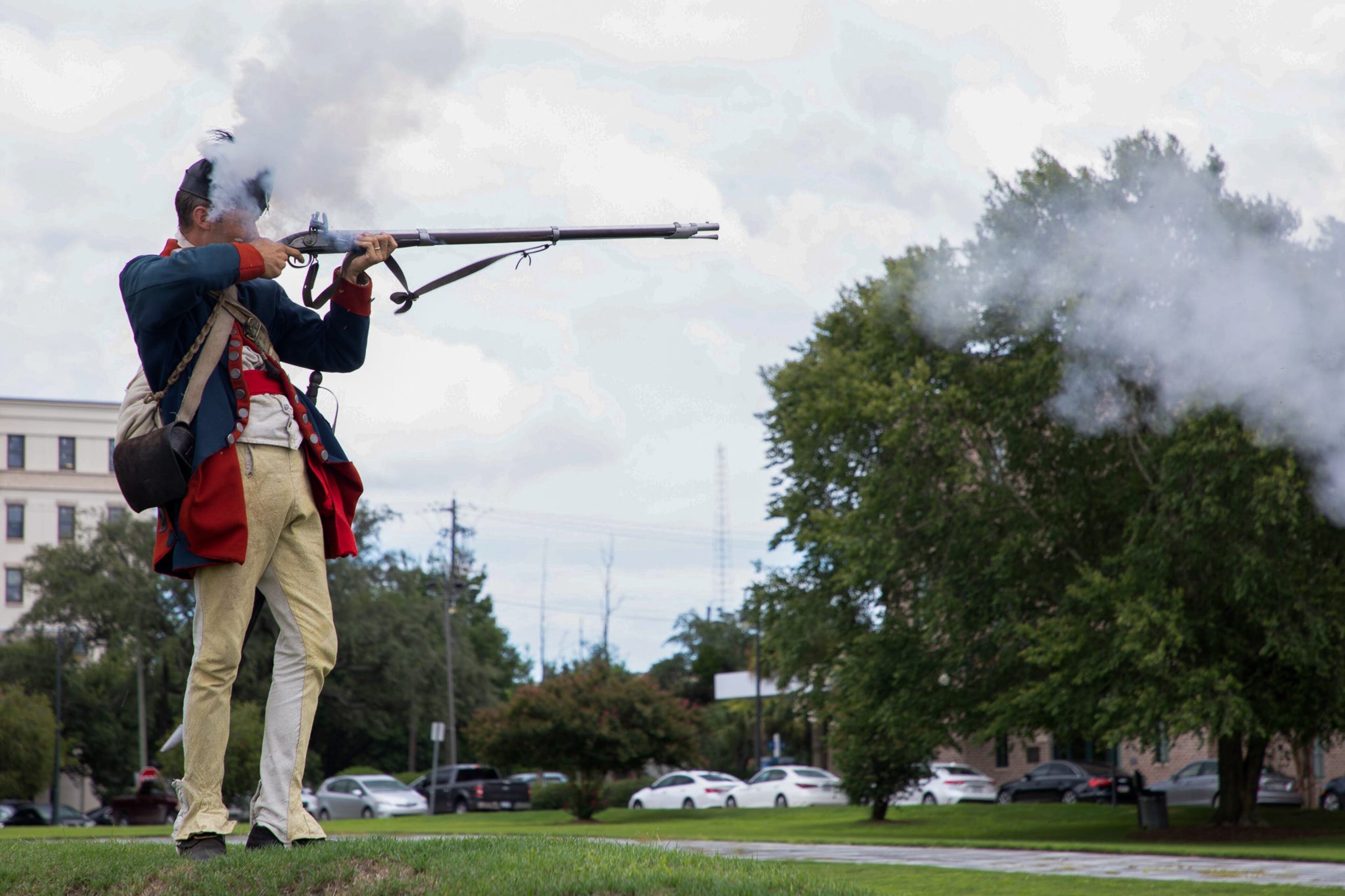 The recoil kicks back against the Coastal Heritage Society's Interpretive Supervisor Aaron Bradford as he fires a blank from a reproduction of a smooth bore flintlock Charleville musket to commemorate the granite bench's dedication on July 14, 2022.