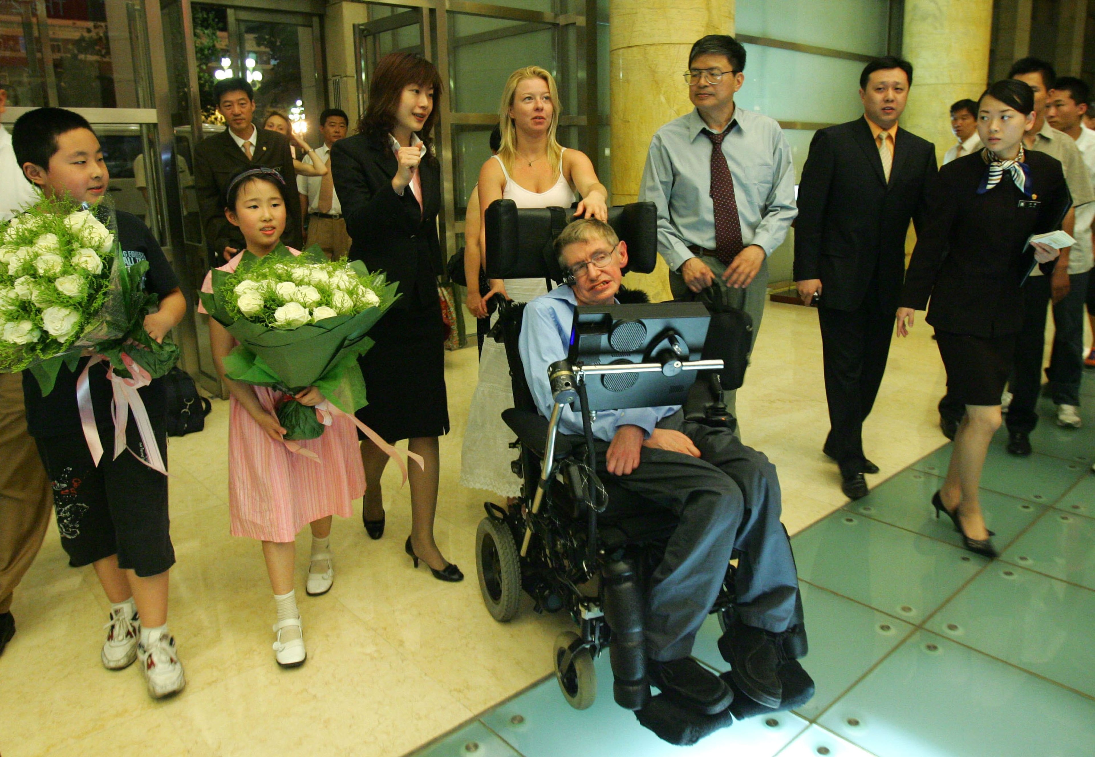 BEIJING, CHINA - JUNE 17: (CHINA OUT) British scientist Stephen Hawking (C), accompanied by his nurse, is welcomed by Chinese people as he arrives at the Beijing Hotel on June 17, 2006 in Beijing, China. Stephen Hawking is visiting Beijing to attend an academic conference, according to state media. (Photo by China Photos/Getty Images)