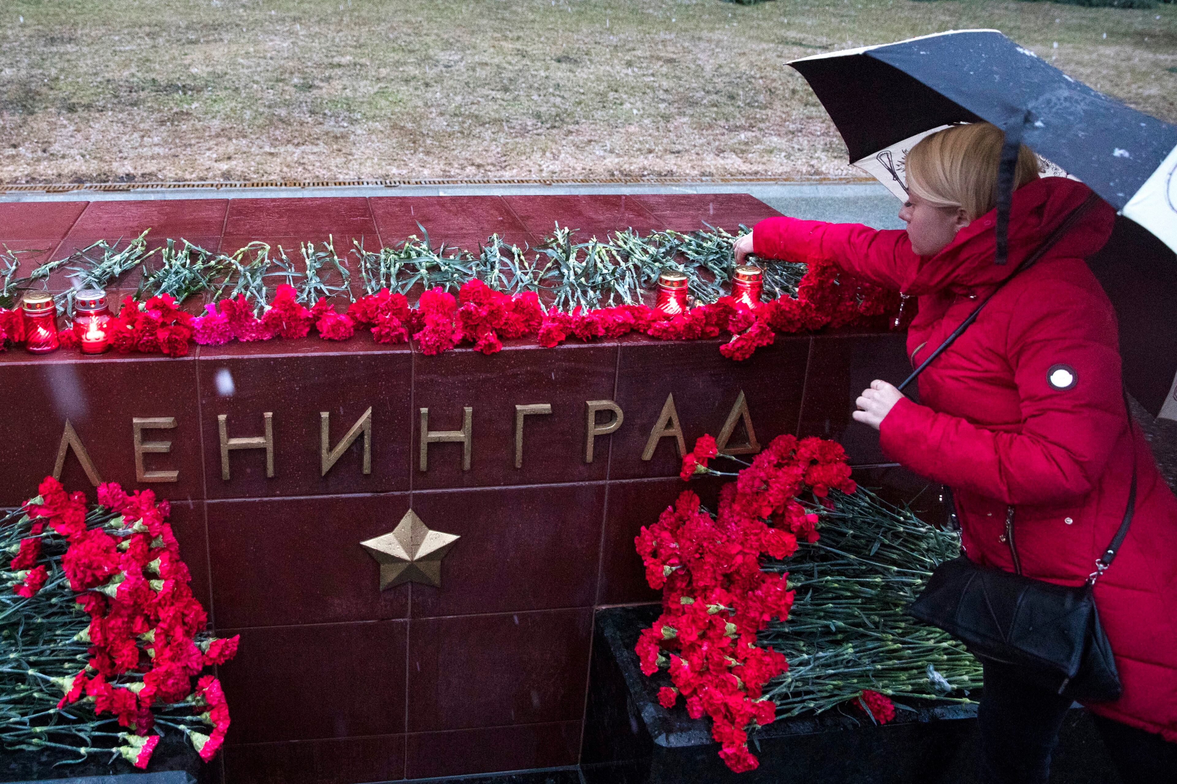A woman lights a candle in memory of victims killed by a bomb blast in a subway train in St. Petersburg at the memorial stone with the word Leningrad (St. Petersburg) at the Tomb of Unknown Soldier in front of the Kremlin wall in Moscow, Russia, Monday, April 3, 2017. A bomb blast tore through a subway train in Russia's second-largest city Monday, killing 10 people and injuring about 40 as President Vladimir Putin visited the city, authorities said. (AP Photo/Pavel Golovkin)