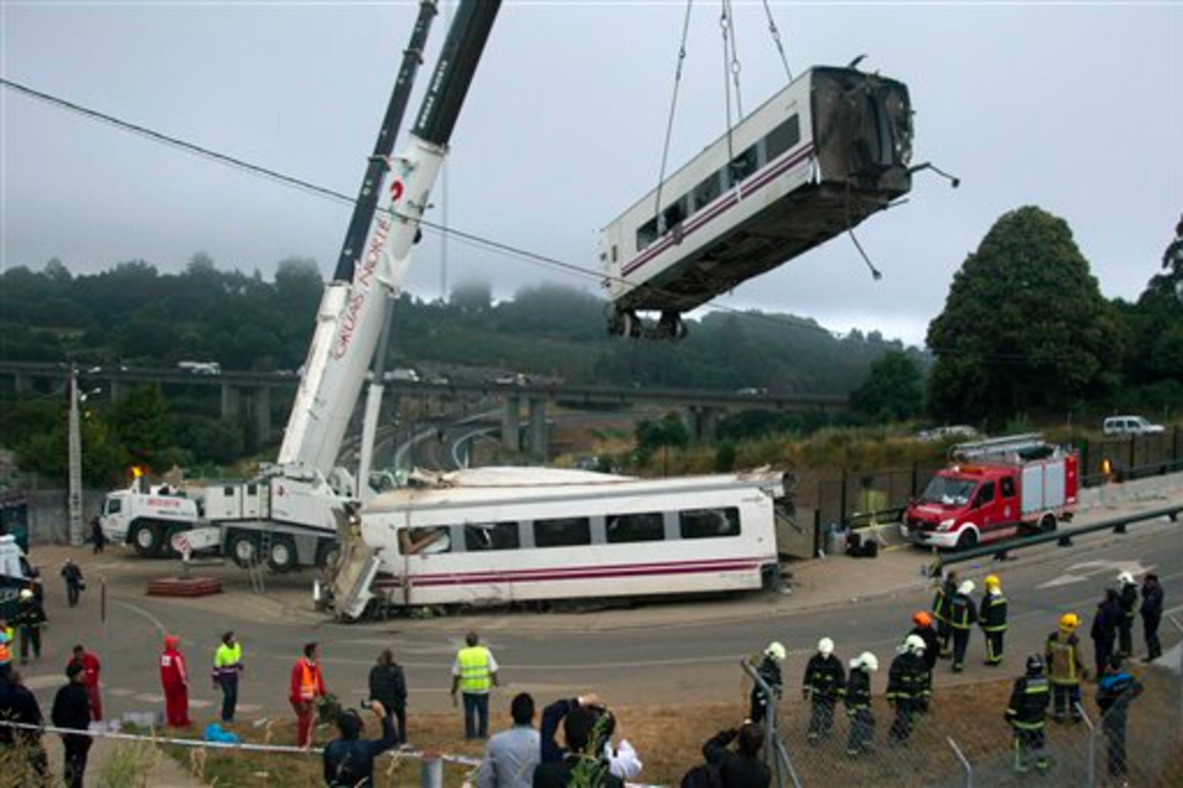 Derailed cars are removed as emergency personnel work at the site of a train accident in Santiago de Compostela, Spain, on Thursday, July 25, 2013. The death toll in the passenger train crash in northwestern Spain rose to 77 on Thursday after the train jumped the tracks on a curvy stretch just before arriving in the northwestern shrine city of Santiago de Compostela, a judicial official said. (AP Photo/ Lalo Villar)