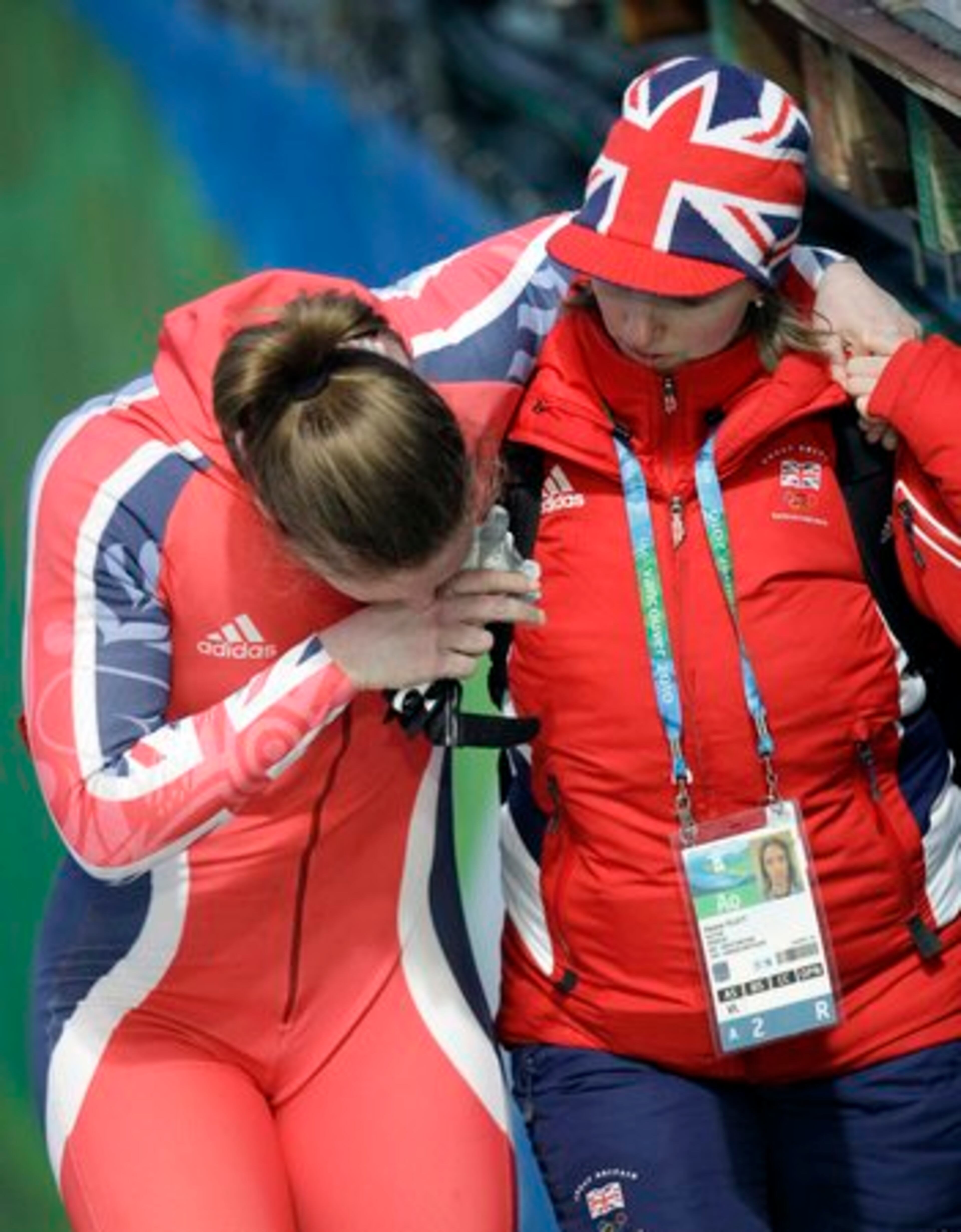 Great Britain's GBR-1, brakeman Gillian Cooke, is helped off the track by team doctor Eleanor Tillett, right, after crashing.