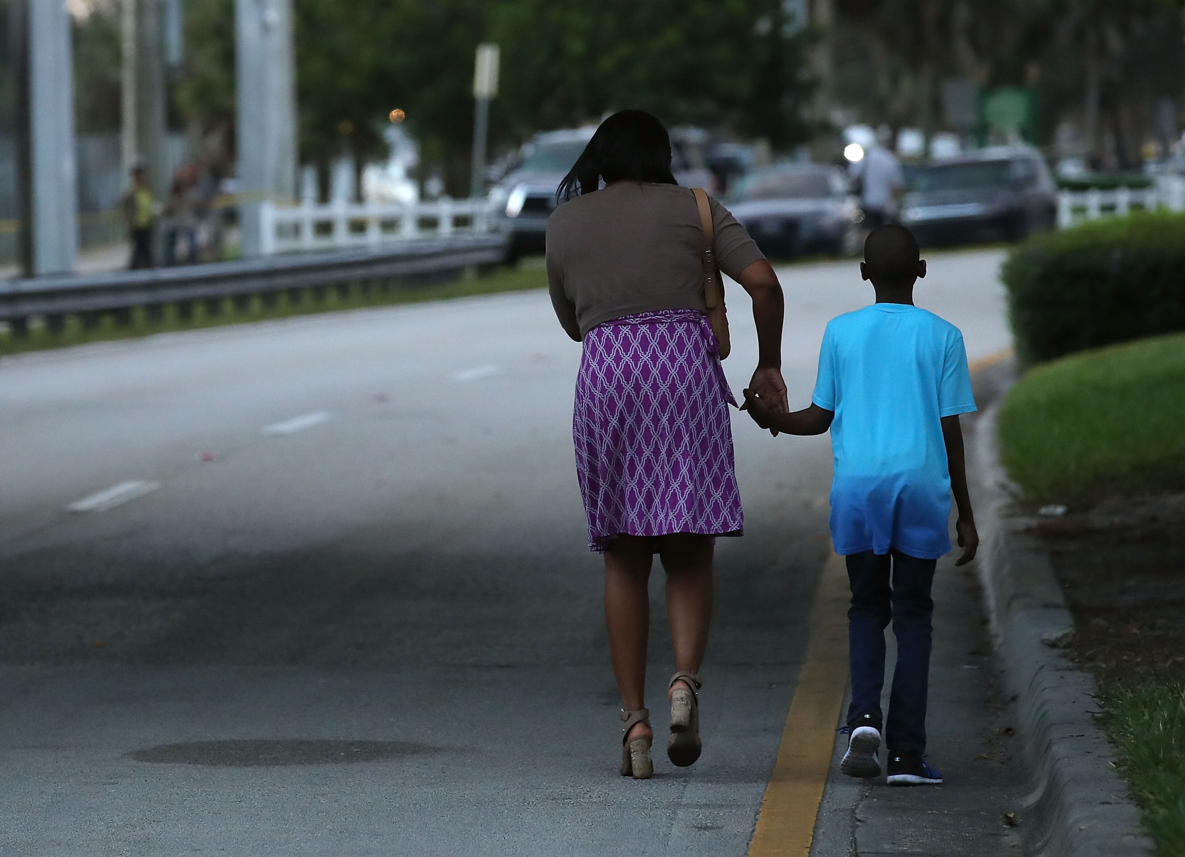 PARKLAND, FL - FEBRUARY 15: Sheree Spaulding walks with her 15-year-old son, Justin Spauling, who is a 9th grader at the Marjory Stoneman Douglas High School where 17 people were killed by a gunman yesterday, on February 15, 2018 in Parkland, Florida. Police arrested the suspect after a short manhunt, and have identified him as 19-year-old former student Nikolas Cruz. (Photo by Mark Wilson/Getty Images)