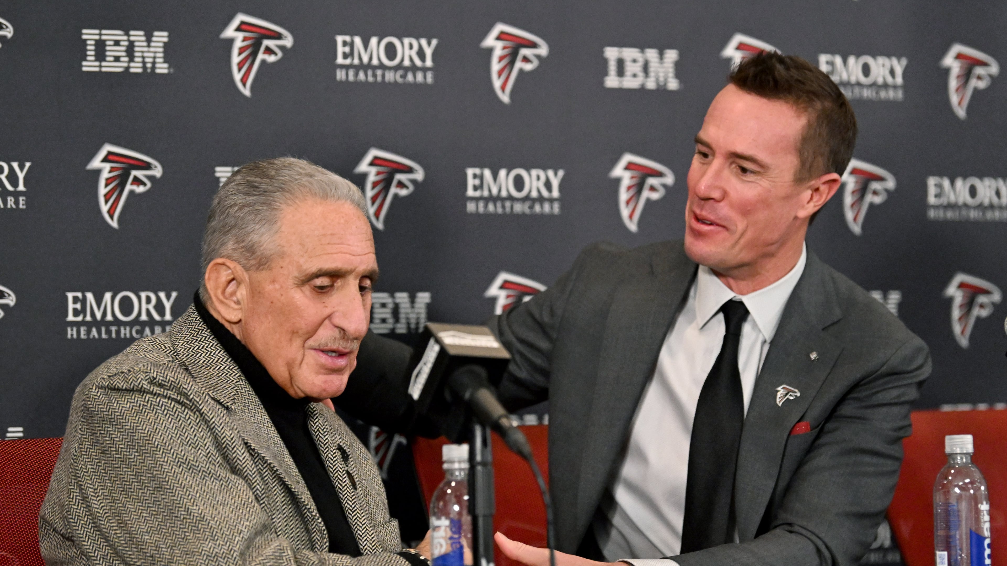 Matt Ryan holds a hand of Atlanta Falcons owner Arthur M. Blank during a news conference to introduce Ryan as the new Falcons president of football, Tuesday, Jan. 13, 2026, in Flowery Branch. (Hyosub Shin/AJC)