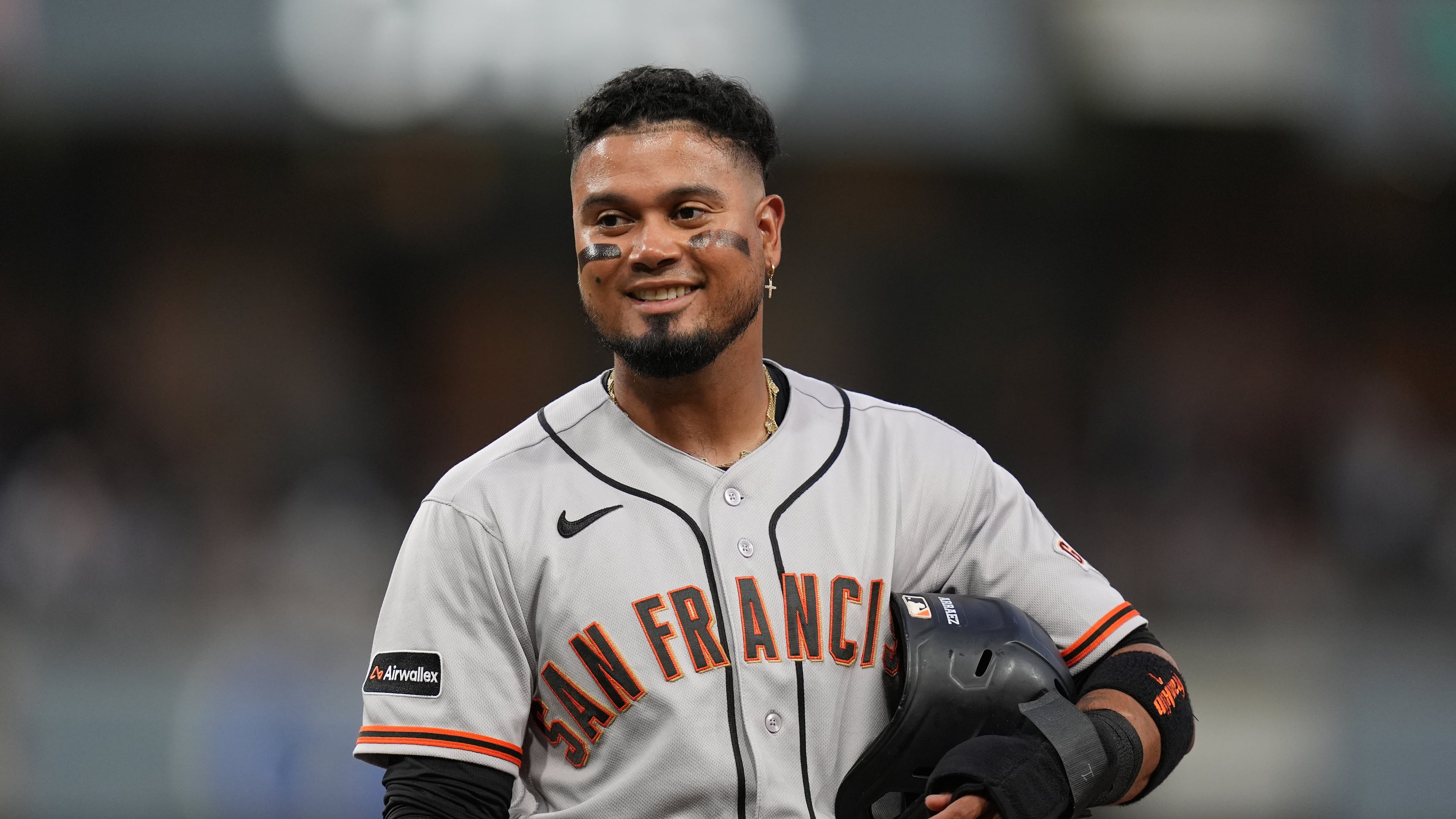 San Francisco Giants' Luis Arraez jokes with players in the San Diego Padres dugout as he stands on first base after getting hit by a pitch during the fourth inning of a baseball game Thursday, July 30, 2026, in San Diego. (AP Photo/Gregory Bull)