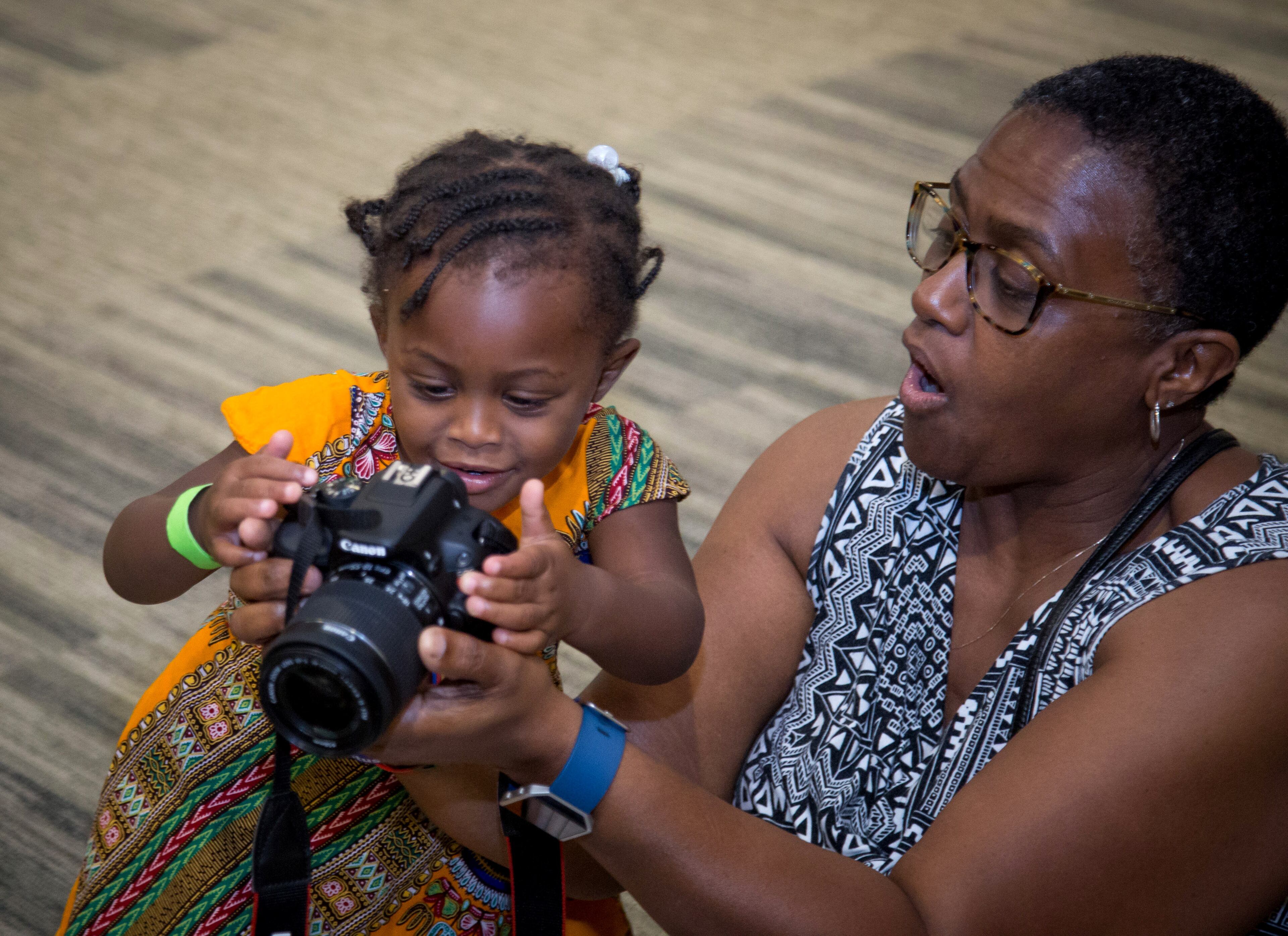 Kim White (R) shows her granddaughter Brooklyn the photographs she has taken of one of the performances during the Atlanta History Center's Juneteenth Jubilee, June 17, 2017. Juneteenth is a celebration commemorating the end of slavery in the United States. STEVE SCHAEFER / SPECIAL TO THE AJC