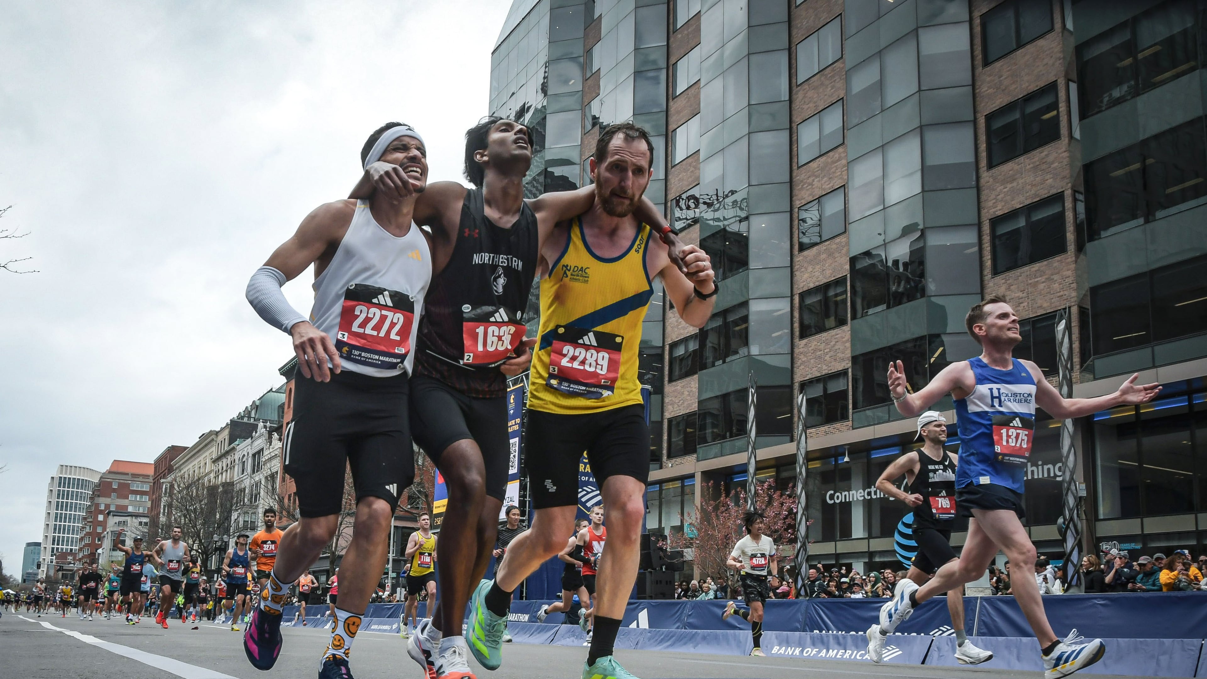 This photo provided by the Boston Athletic Association and Marathonfoto shows Boston Marathon runners Robson De Oliveira of Brazil, left, and Aaron Beggs, of Britain, right, helping runner Ajay Haridasse and helped him across the finish line Monday, April 20, 2026, in Boston. (Gustavo E. Gargallo/Boston Athletic Association/MarathonFoto via AP)