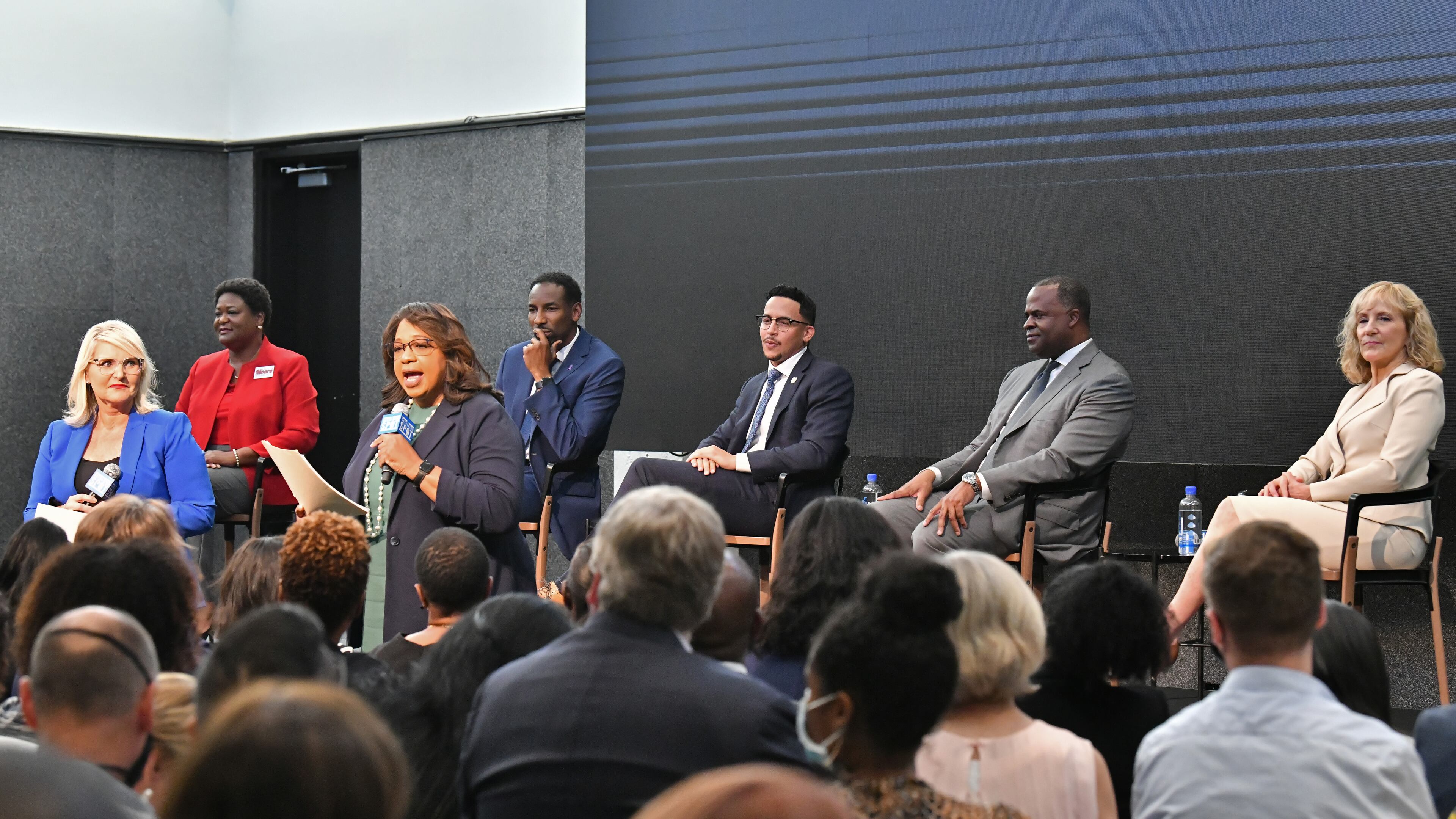 Mayoral candidates (background from left) Felicia Moore, Andre Dickens, Antonio Brown, Kasim Reed and Sharon Gay sit as hosts Lori Geary Talbert (left) and Condace Pressley speak during City of Atlanta Mayoral Debate at The Gathering Spot in Atlanta on Thursday, October 7, 2021. (Hyosub Shin / Hyosub.Shin@ajc.com)